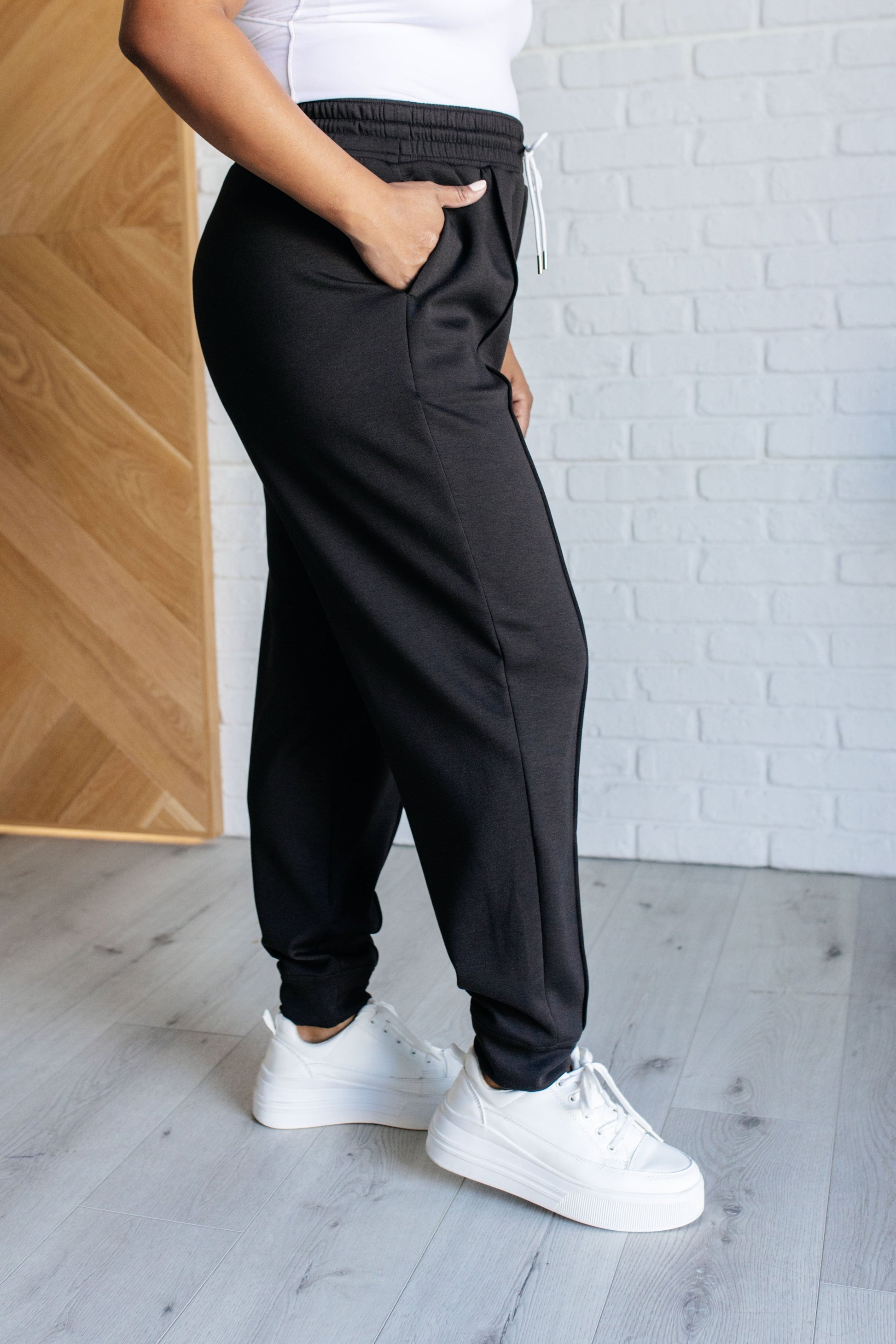 Center Seam Scuba Joggers in black featuring a front seam, elastic waistline with functional drawstring, side pockets, and banded hem for a comfortable and stylish fit.