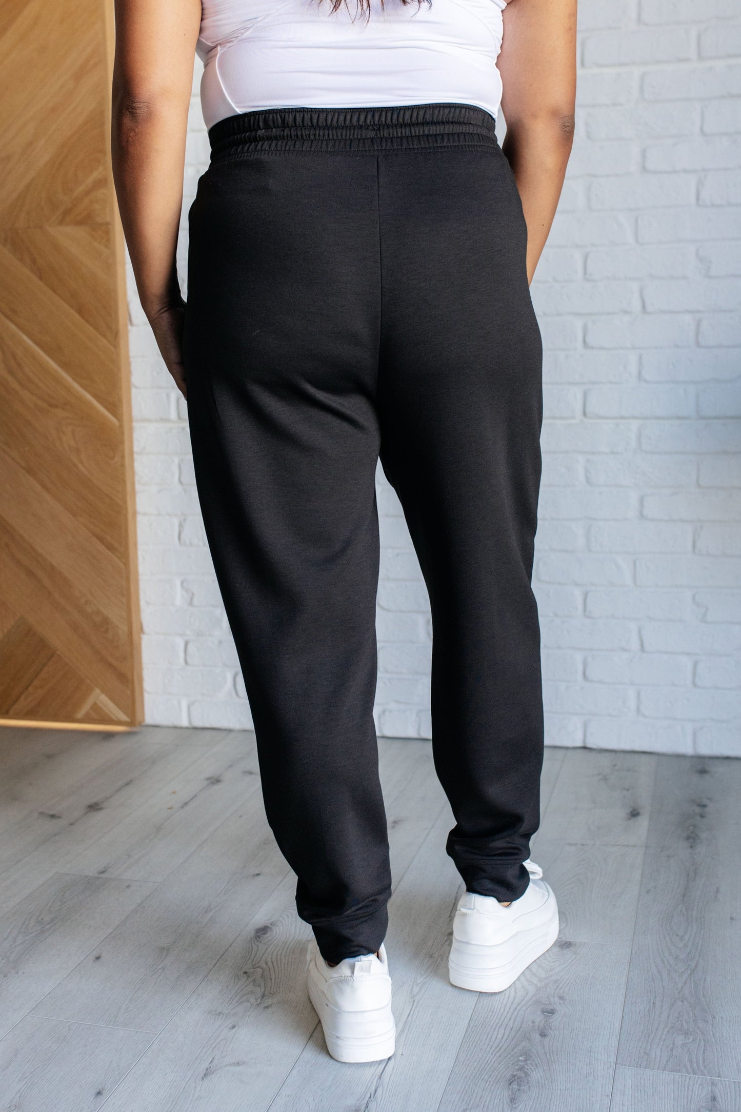 Center Seam Scuba Joggers in black featuring a front seam, elastic waistline with functional drawstring, side pockets, and banded hem for a comfortable and stylish fit.