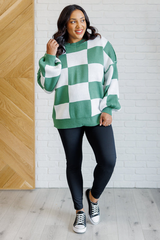 A women's green and white checkered sweater with a round neckline, long sleeves with drop shoulders, exaggerated ribbed cuffs, exposed seam, and a banded ribbed hemline.