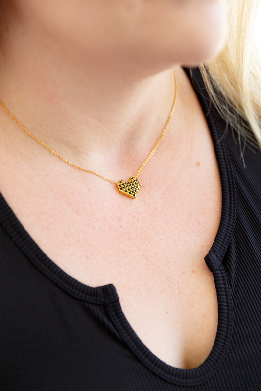 A checkered heart necklace with 18k gold-plated stainless steel, featuring green faceted stones in a checkerboard design on a heart-shaped pendant. 