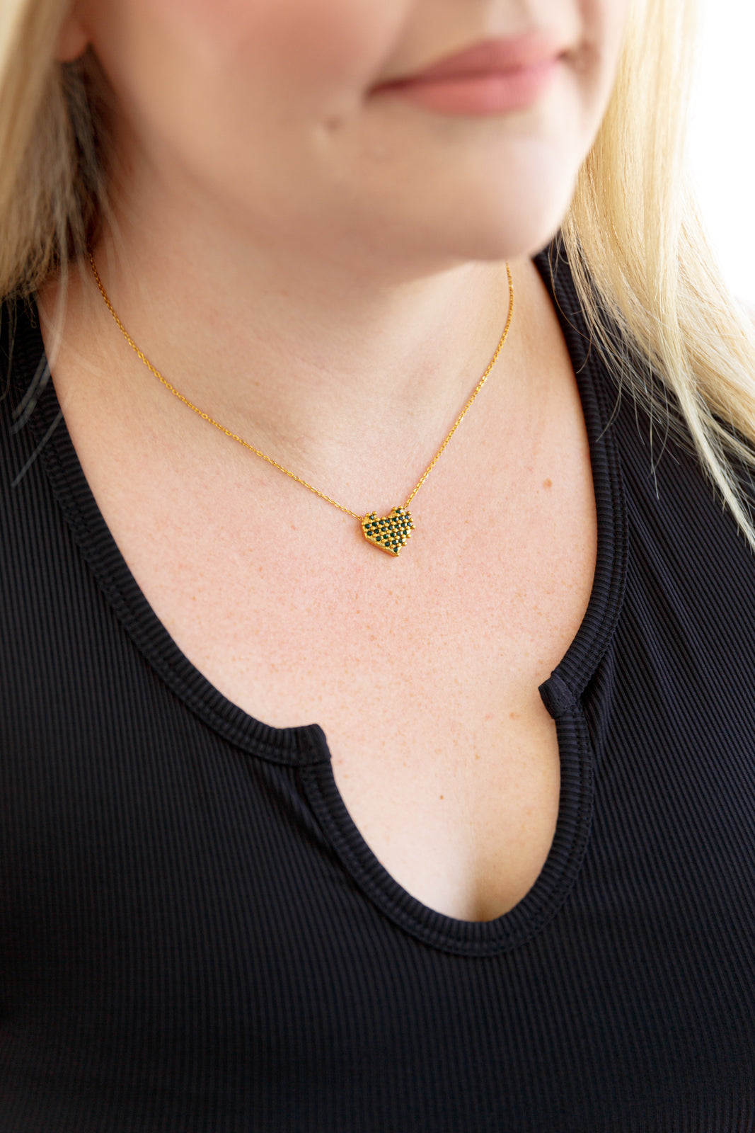 A checkered heart necklace with 18k gold-plated stainless steel, featuring green faceted stones in a checkerboard design on a heart-shaped pendant. 