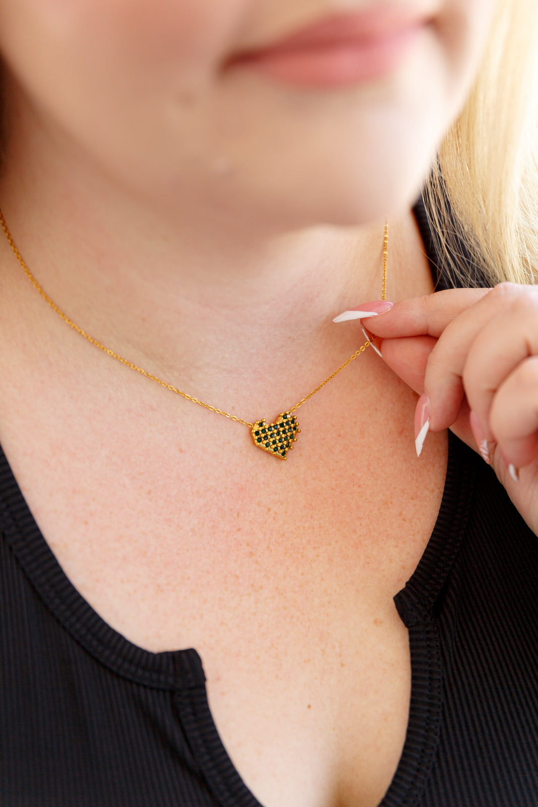 A checkered heart necklace with 18k gold-plated stainless steel, featuring green faceted stones in a checkerboard design on a heart-shaped pendant. 