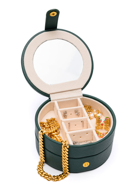 Circular Travel Jewelry Case in Green, with secure snap closure, small mirror, six ring slots, four perforated sections for earrings, six compartments for jewelry, and three necklace hooks.