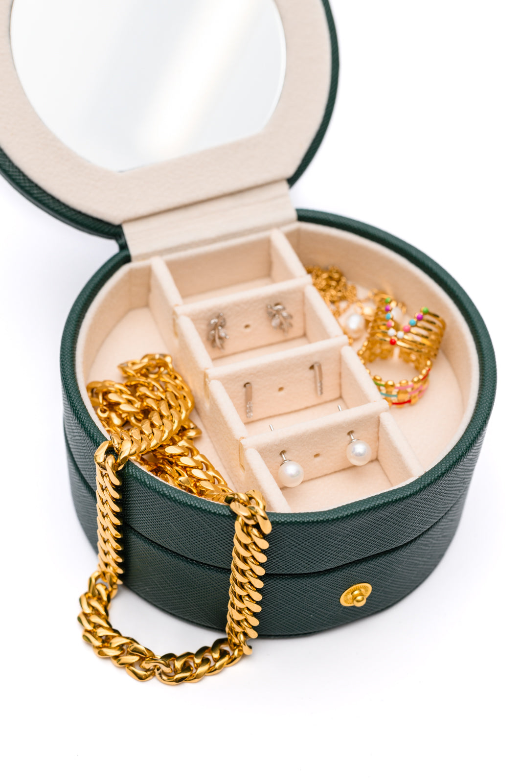 Circular Travel Jewelry Case in Green, featuring a waterproof exterior, secure snap closure, small mirror, six ring slots, four perforated sections for earrings, six compartments for jewelry, and three necklace hooks. 