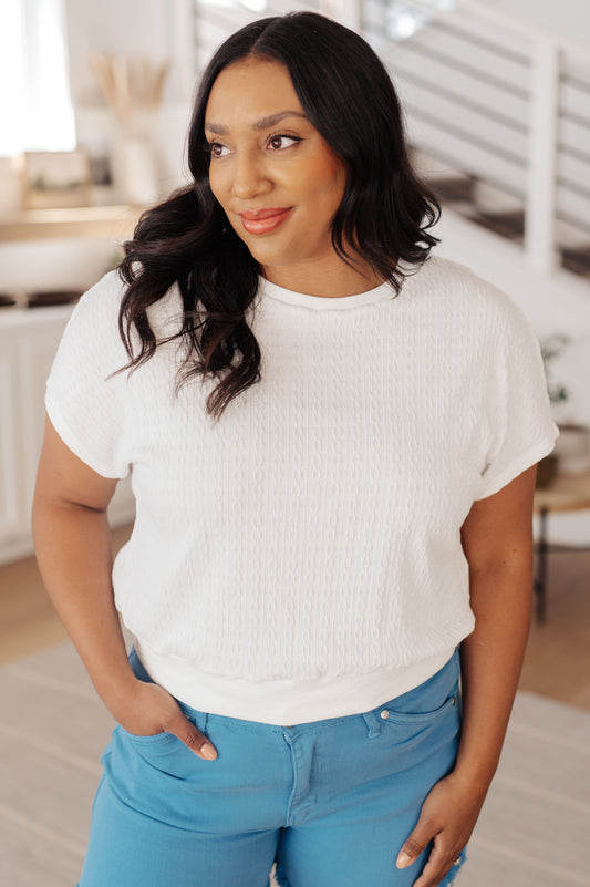 Plus size model front view of Claudine cable knit short sleeve top with ribbed neckline and cropped fit.