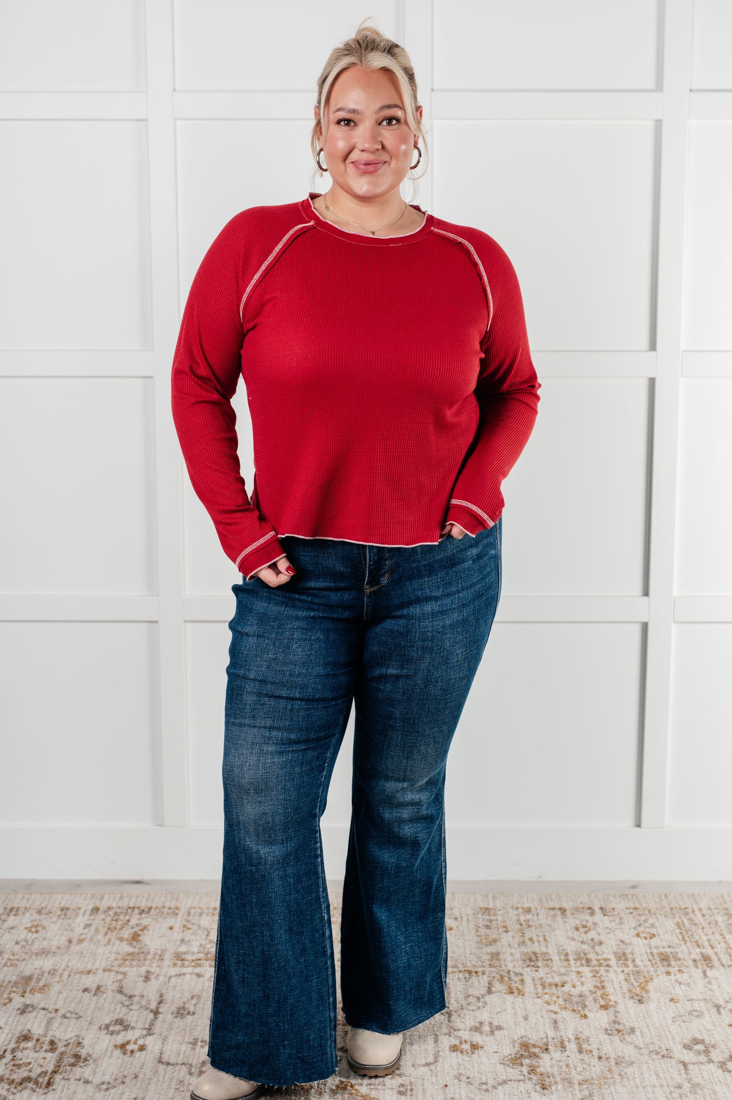 Red waffle knit top with raglan sleeves, exposed seams, and contrast stitching for a stylish and comfortable look. Features raw edges and light stretch.