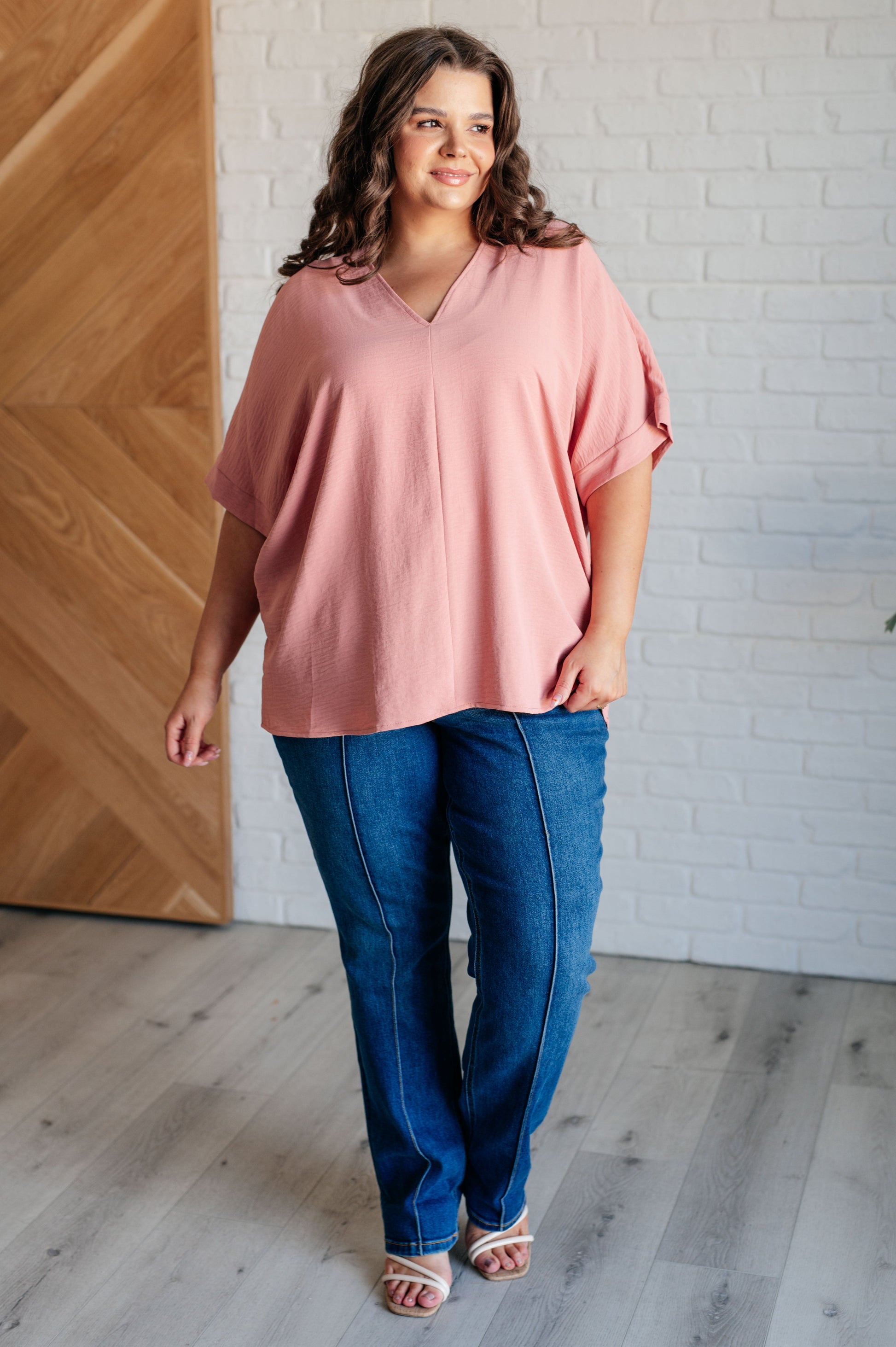 A blush-colored blouse with a V-neckline and relaxed fit. It has dolman short sleeves with banded cuffs, made from crinkle woven fabric for a stylish, easy look.