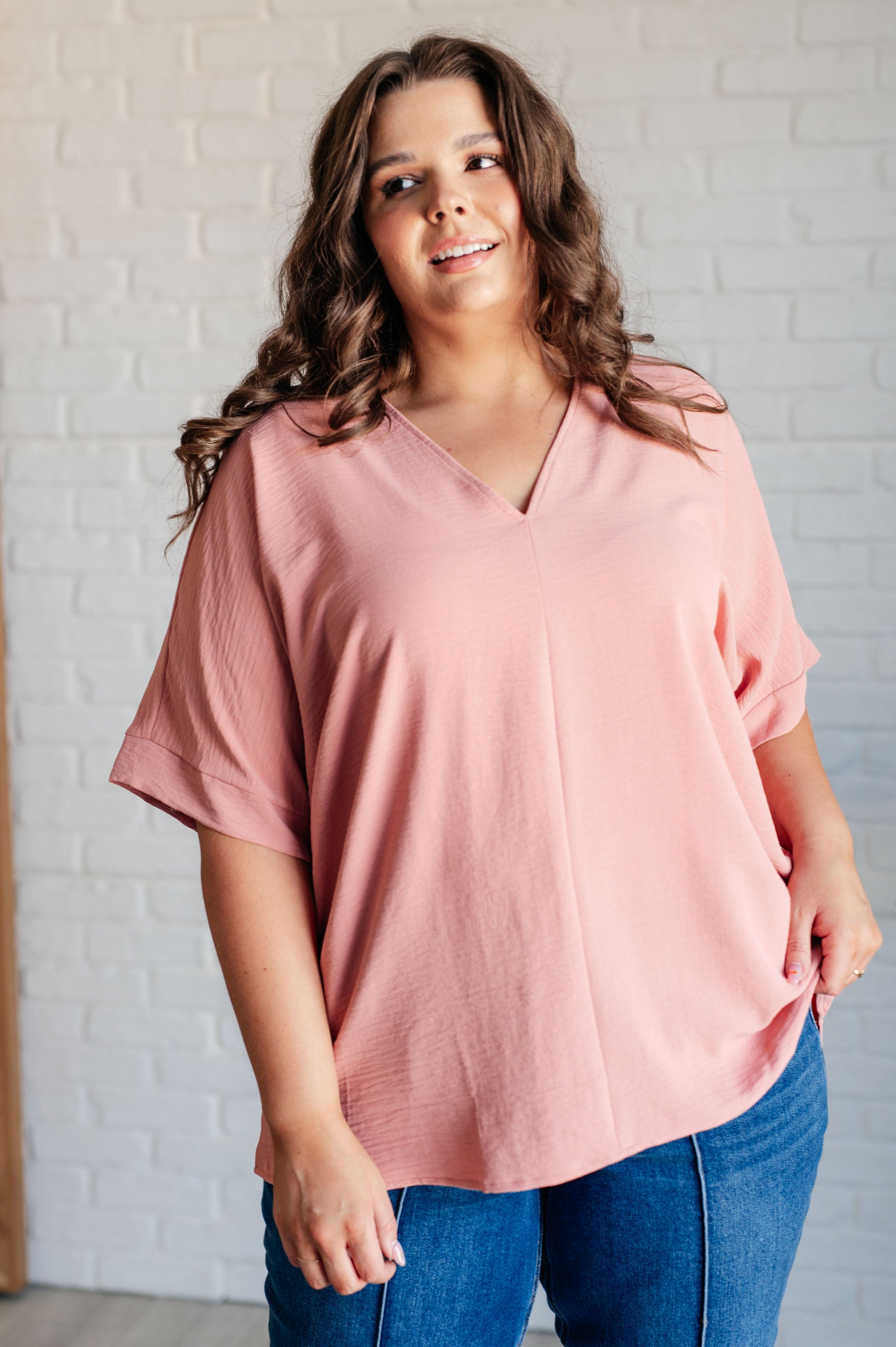 A blush-colored blouse with a V-neckline and relaxed fit. It has dolman short sleeves with banded cuffs, made from crinkle woven fabric for a stylish, easy look.