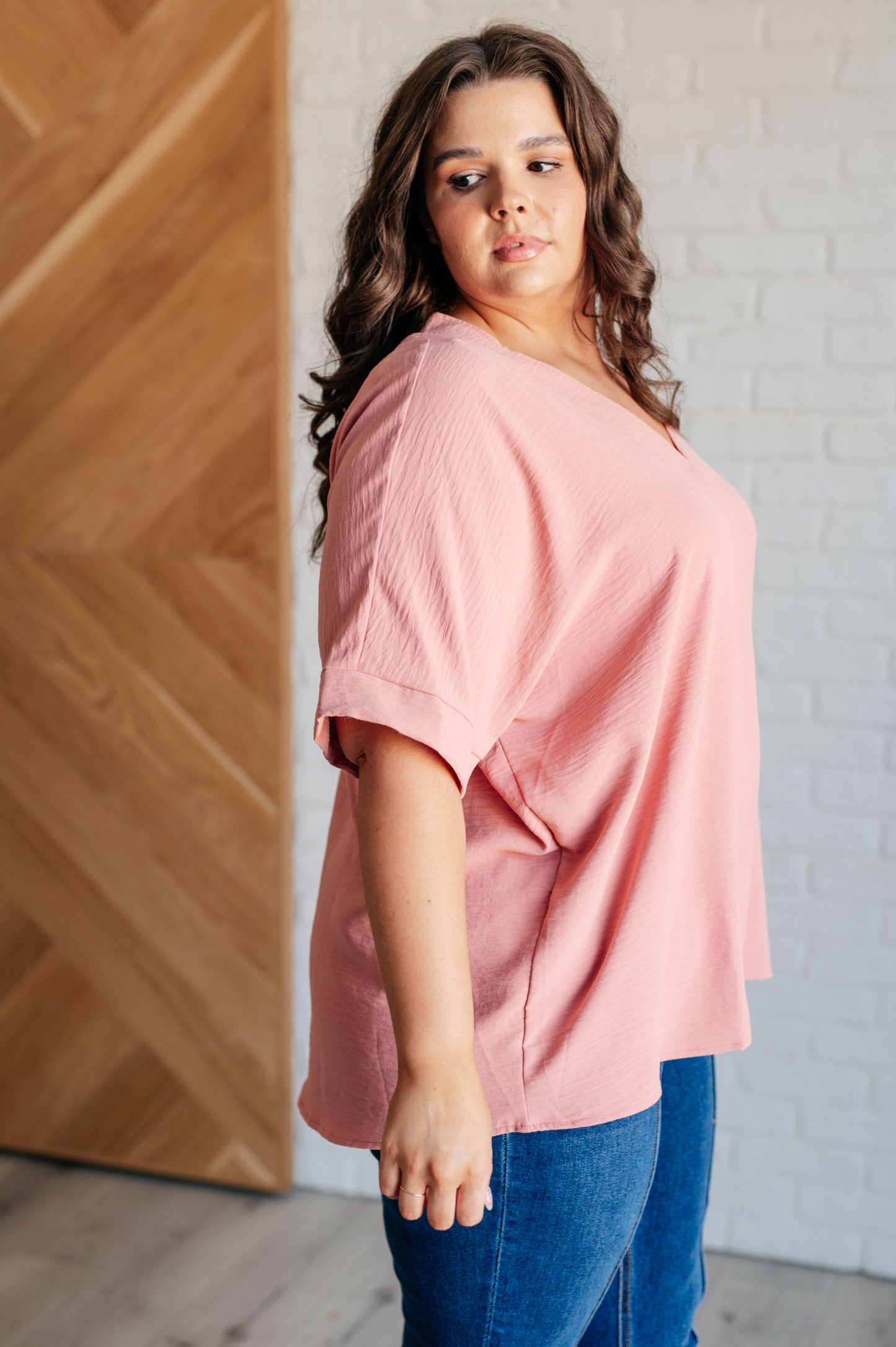 A blush-colored blouse with a V-neckline and relaxed fit. It has dolman short sleeves with banded cuffs, made from crinkle woven fabric for a stylish, easy look.