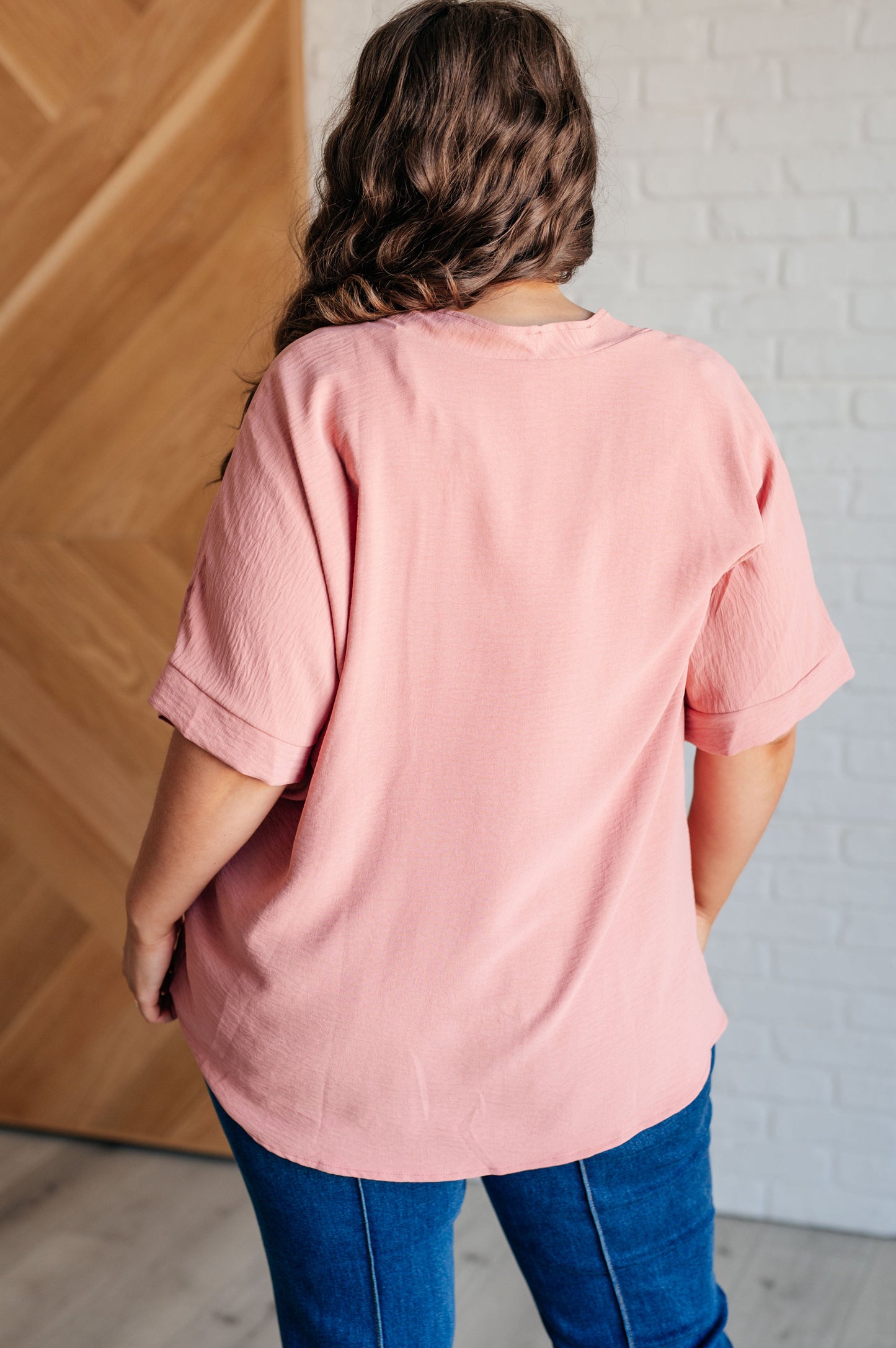 A blush-colored blouse with a V-neckline and relaxed fit. It has dolman short sleeves with banded cuffs, made from crinkle woven fabric for a stylish, easy look.