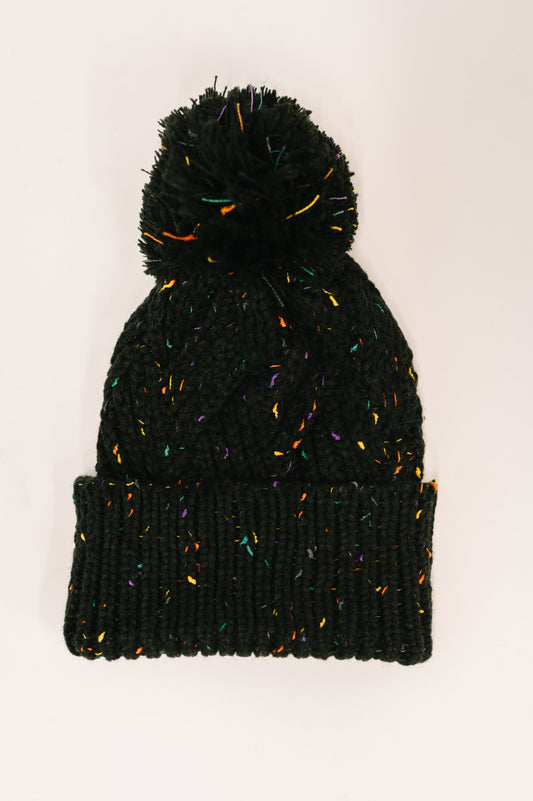 Flat lay of Cover Your Ears Pom Pom Beanie in black with cable knit and pom pom.