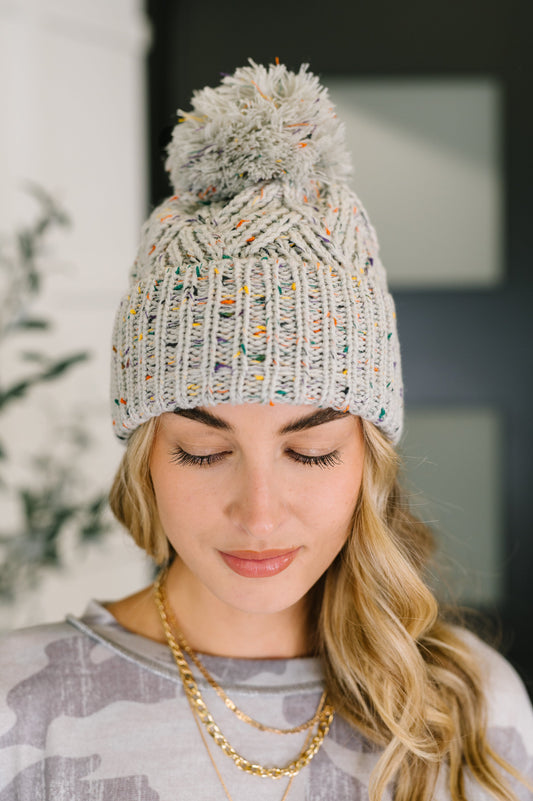 Cover Your Ears Pom Pom Beanie in gray speckled cable knit with fluffy pom.