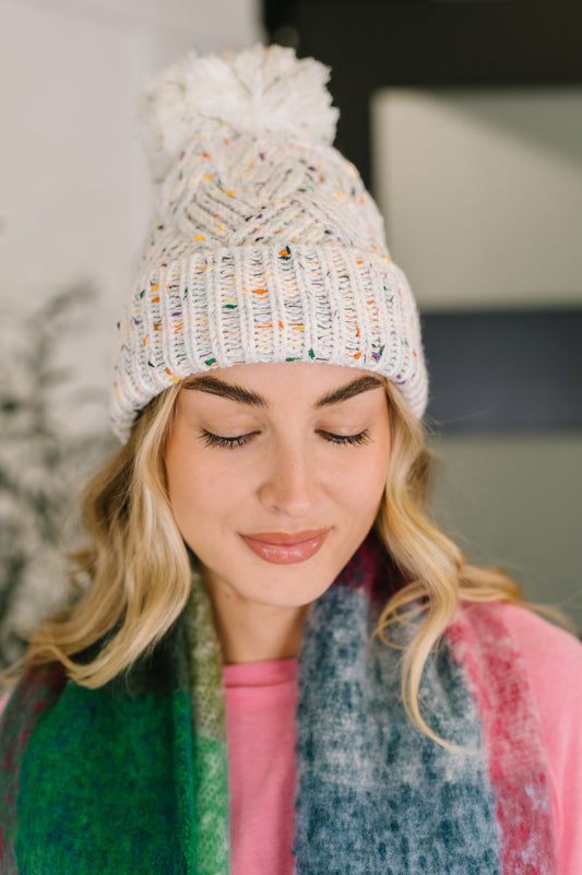 Cover Your Ears Pom Pom Beanie in ivory speckled cable knit with fluffy pom.