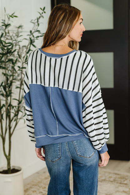 Back view striped crew neck pullover with exposed seam and denim detail.