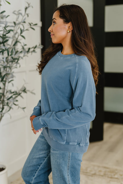Side profile of Nicia Dusty Blue Mineral Wash Pullover, ribbed cuff sleeve and relaxed silhouette