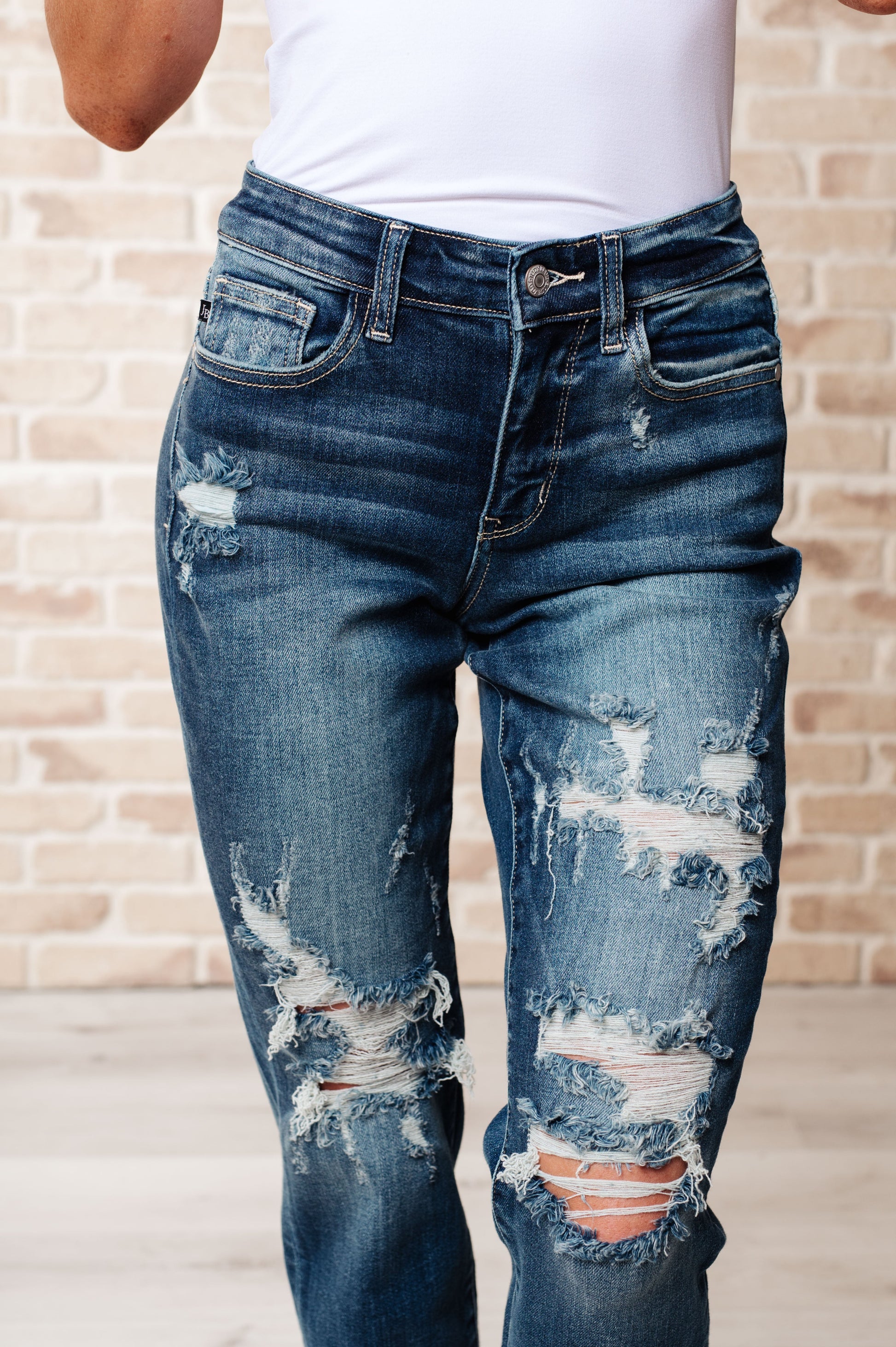 Close-up front view of Danny boyfriend jeans showing mid rise fit, heavy distressing, and dark wash denim with cuffed hem.