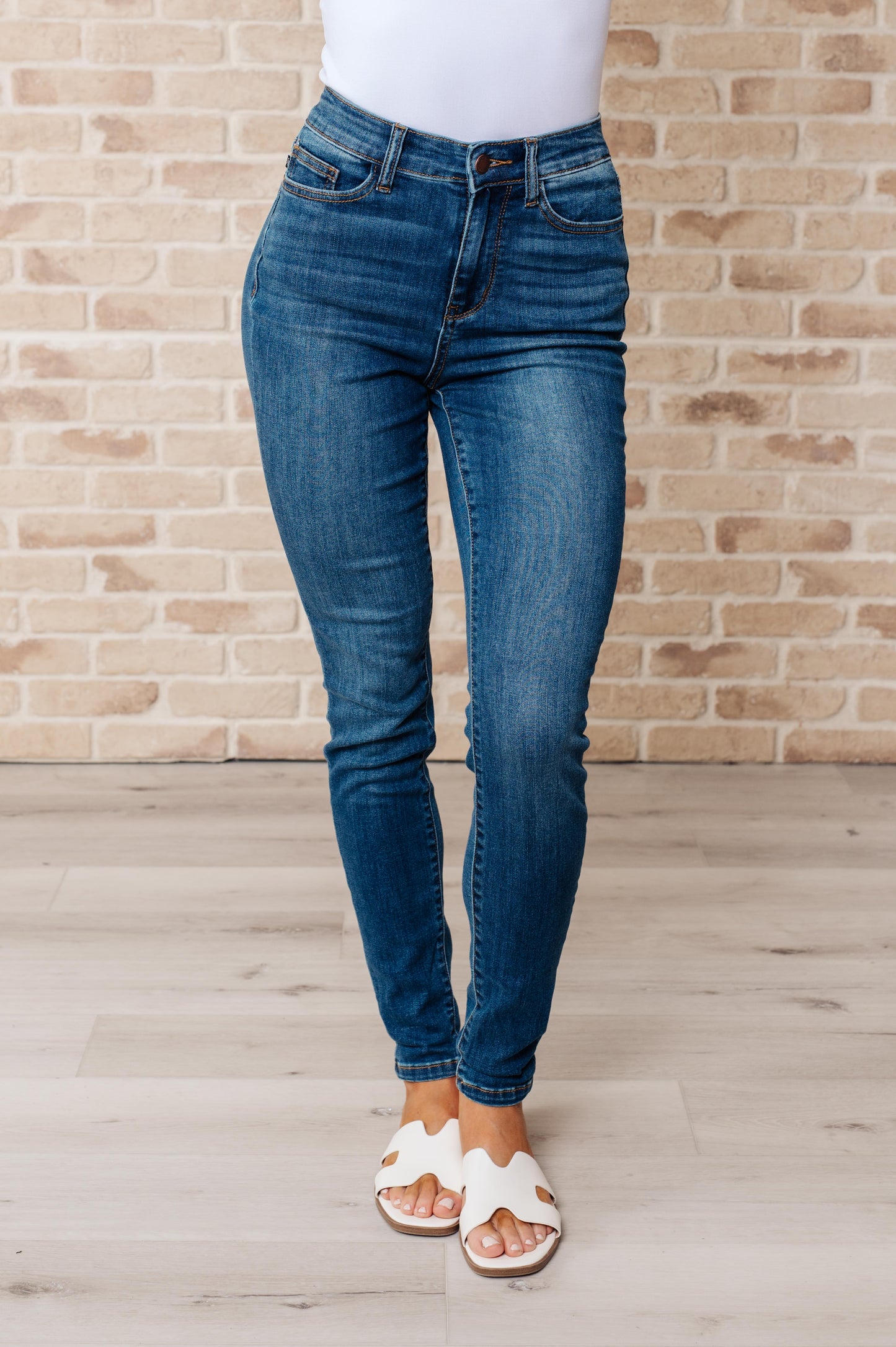 Dark wash high-rise skinny jeans with 4-way stretch for a comfortable fit, featuring a zip fly closure and undistressed design.