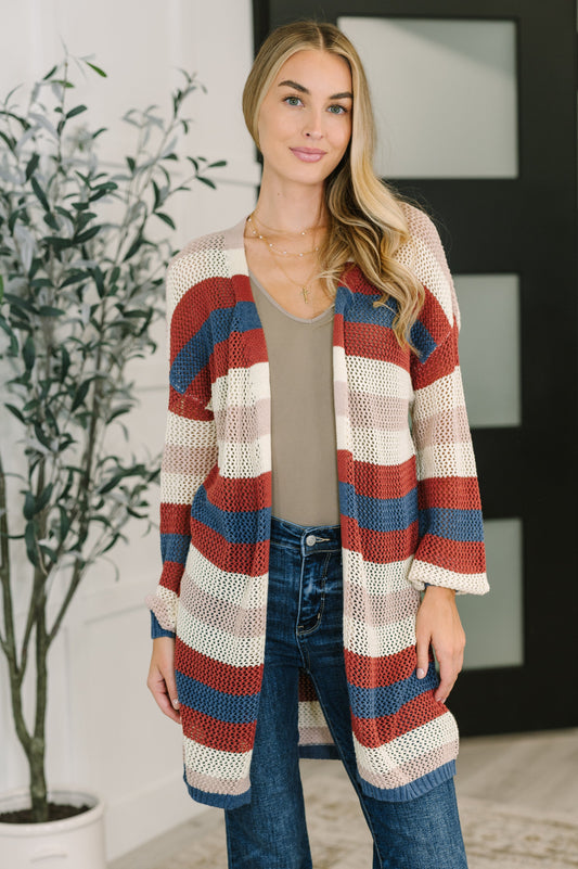 Model wearing Carly Striped Knit Cardigan in rust with beige, cream, and navy stripes.