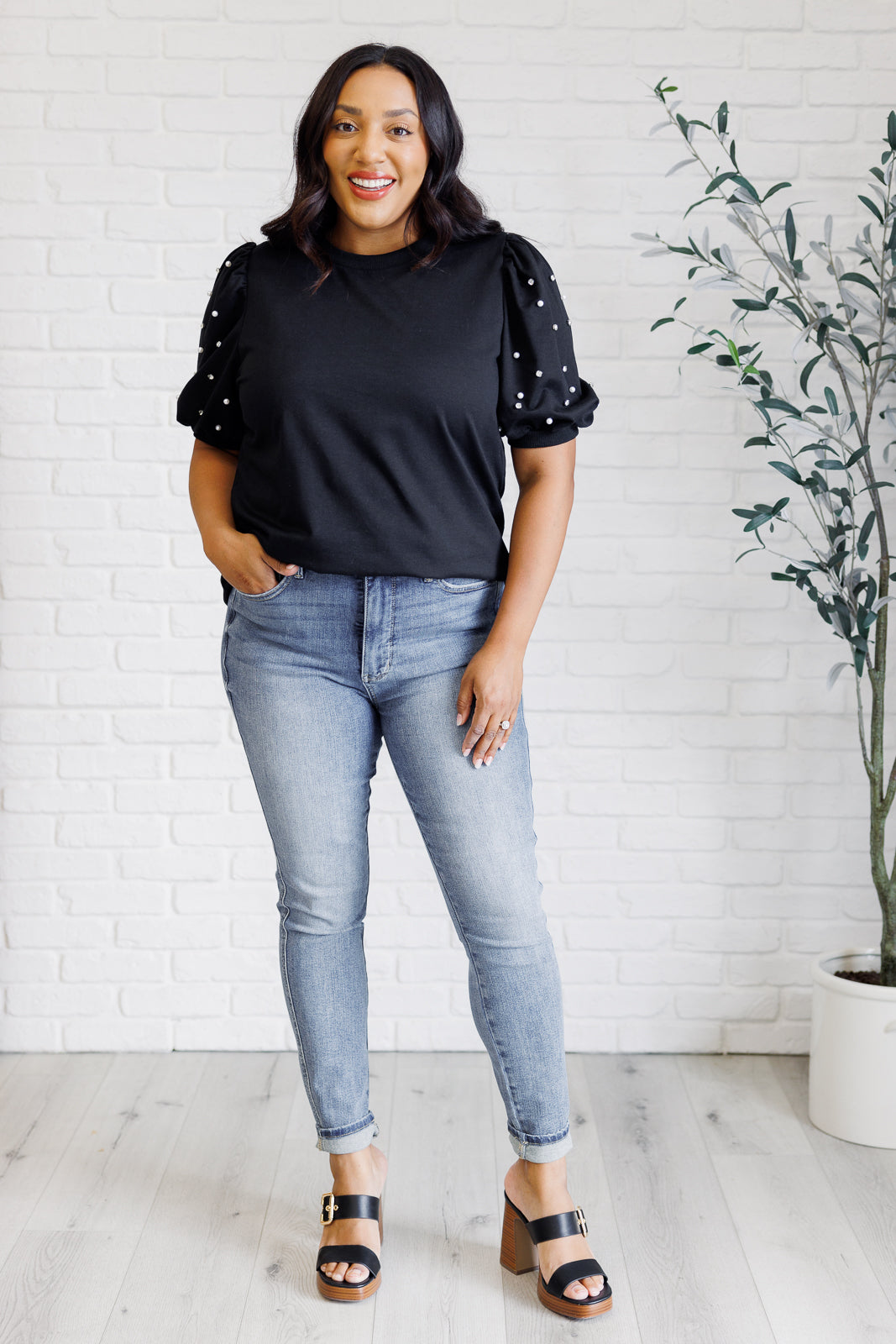 Black French terry top with a ribbed neckline, short balloon sleeves embellished with pearl and faux diamond accents, and ribbed sleeve cuffs.