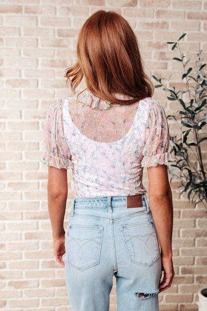 Back view of pink floral bodysuit with mesh stretch fabric and smooth silhouette.