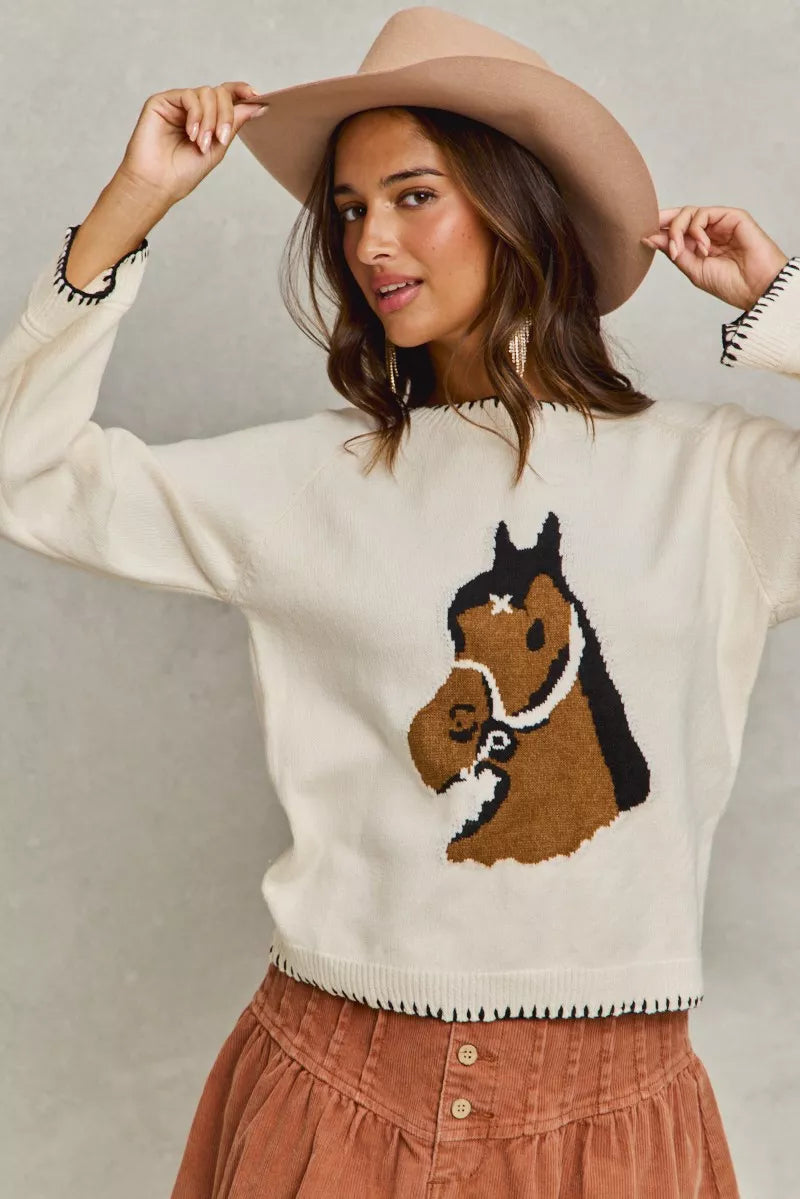 Model adjusting Dolly Horse Knit Sweater Top to show relaxed cozy fit.