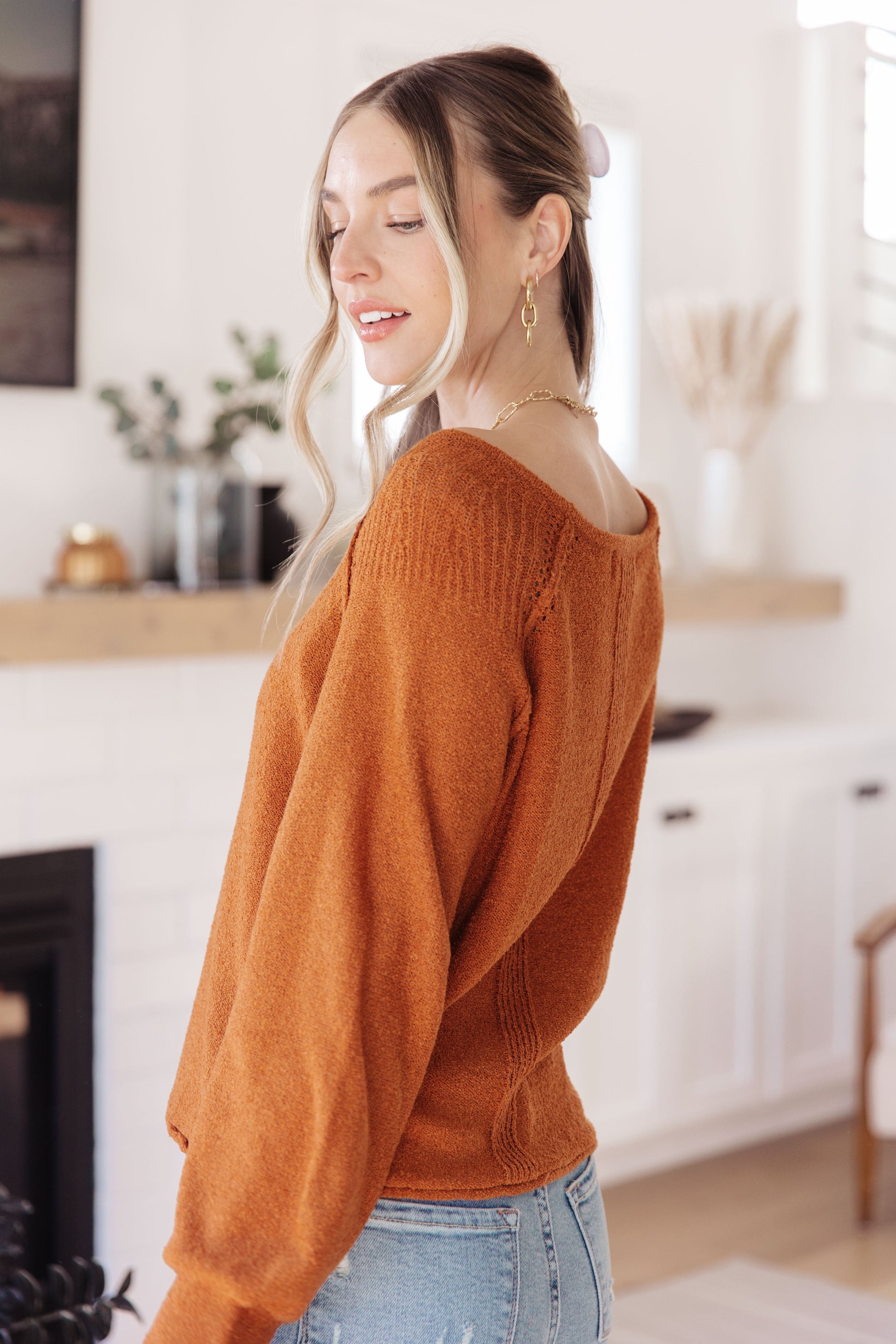 Side view of rust Dorothy Sweater with relaxed fit, cuffed sleeves, and rolled hem