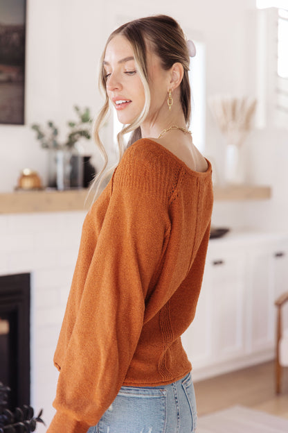 Side view of rust Dorothy Sweater with relaxed fit, cuffed sleeves, and rolled hem