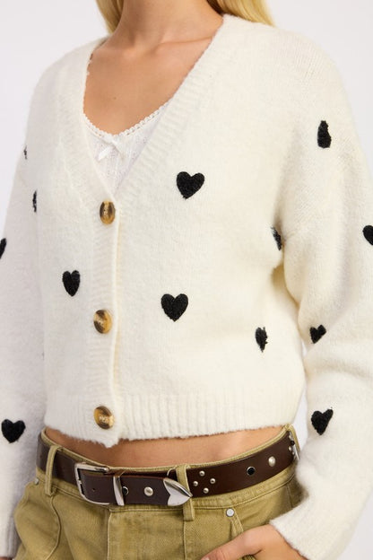 Close-up of Donna Cropped Cardigan in ivory showing black embroidered heart pattern.
