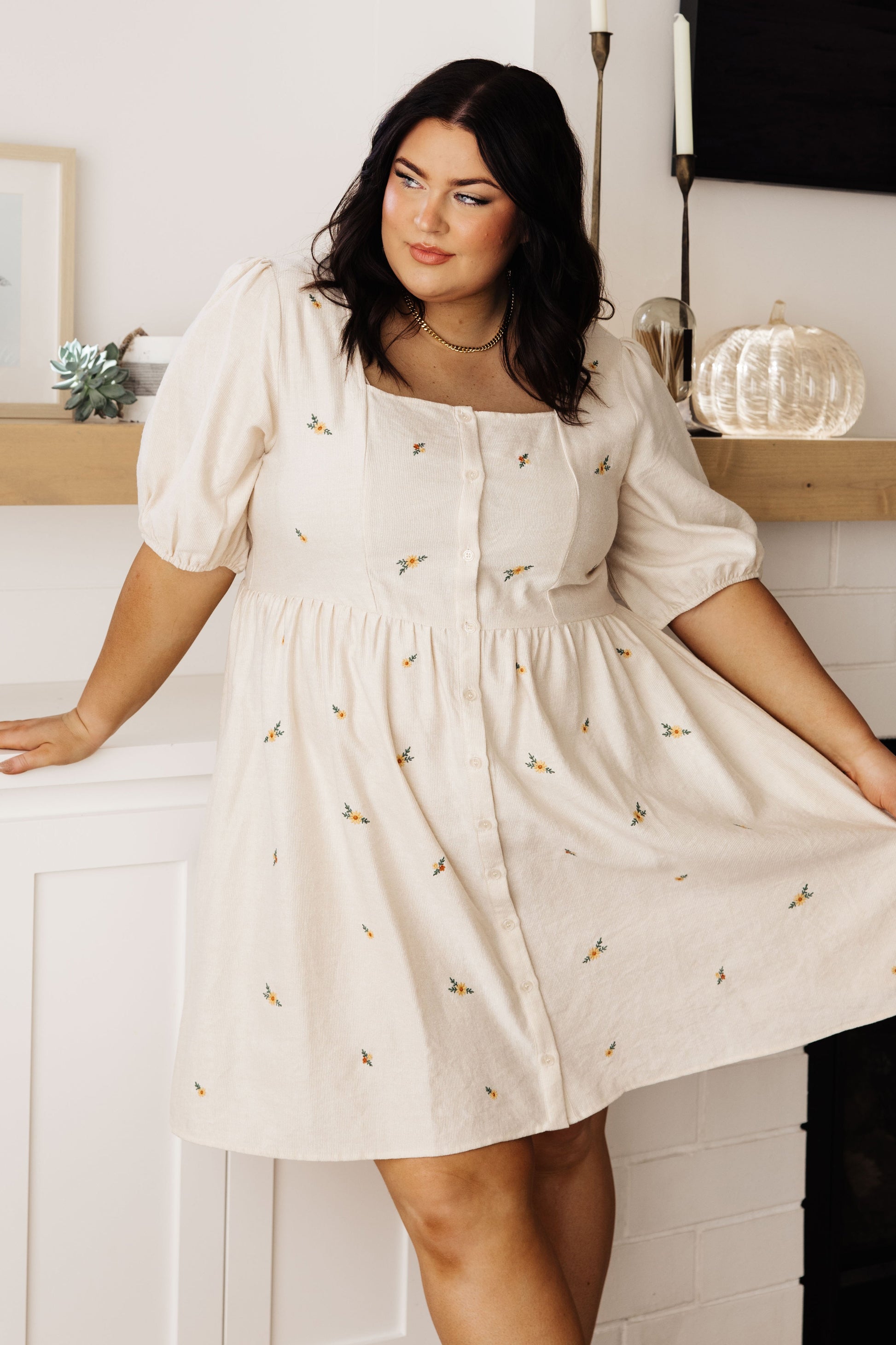 Lightweight cream small wale corduroy dress with floral embroidery, puff short sleeves, square neckline, button-down front, and side seam pockets. 