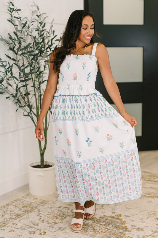 Full body view of Maisy Floral Midi Dress with smocked bodice, ruffle trim, and colorful floral print with blue accents.
