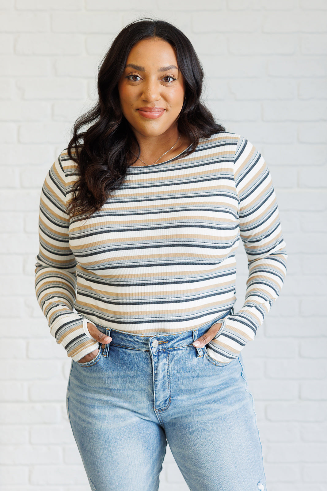 Women's ribbed knit striped top with a round neckline, long sleeves, thumbholes, and side slits.