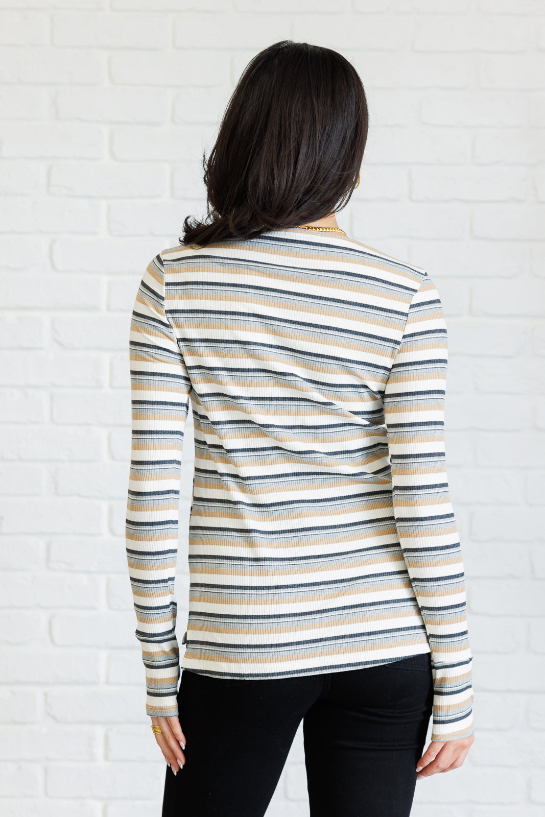 Women's ribbed knit striped top with a round neckline, long sleeves, thumbholes, and side slits.