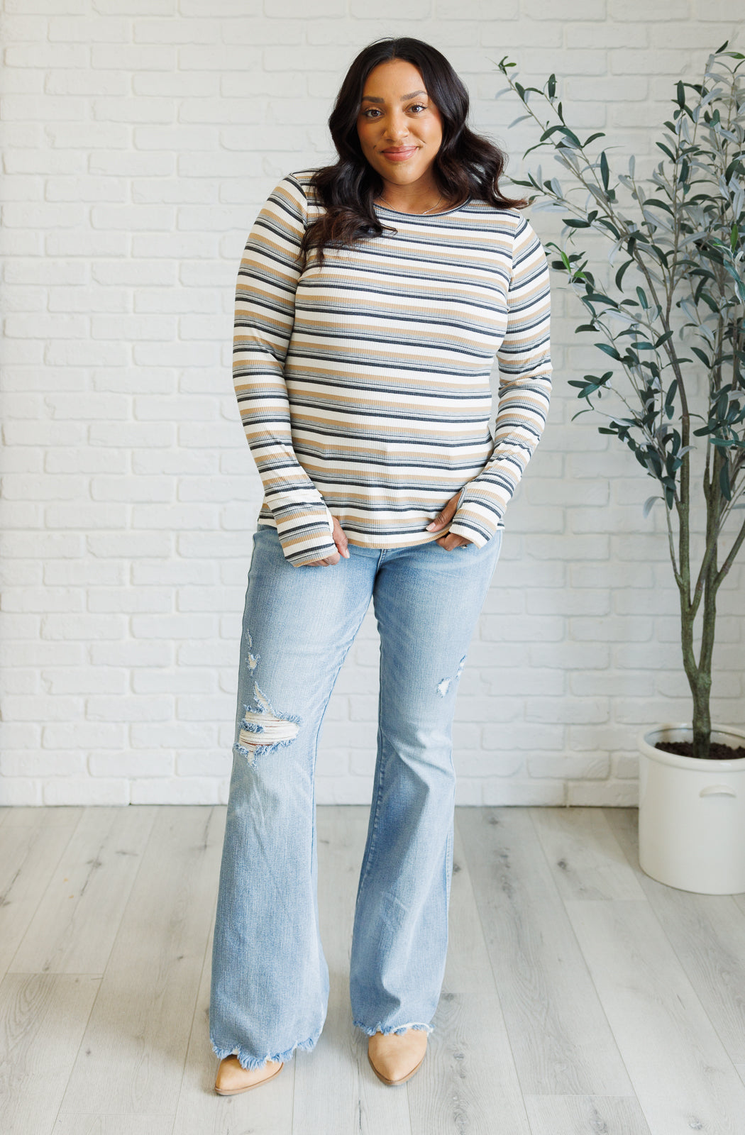 Women's ribbed knit striped top with a round neckline, long sleeves, thumbholes, and side slits.