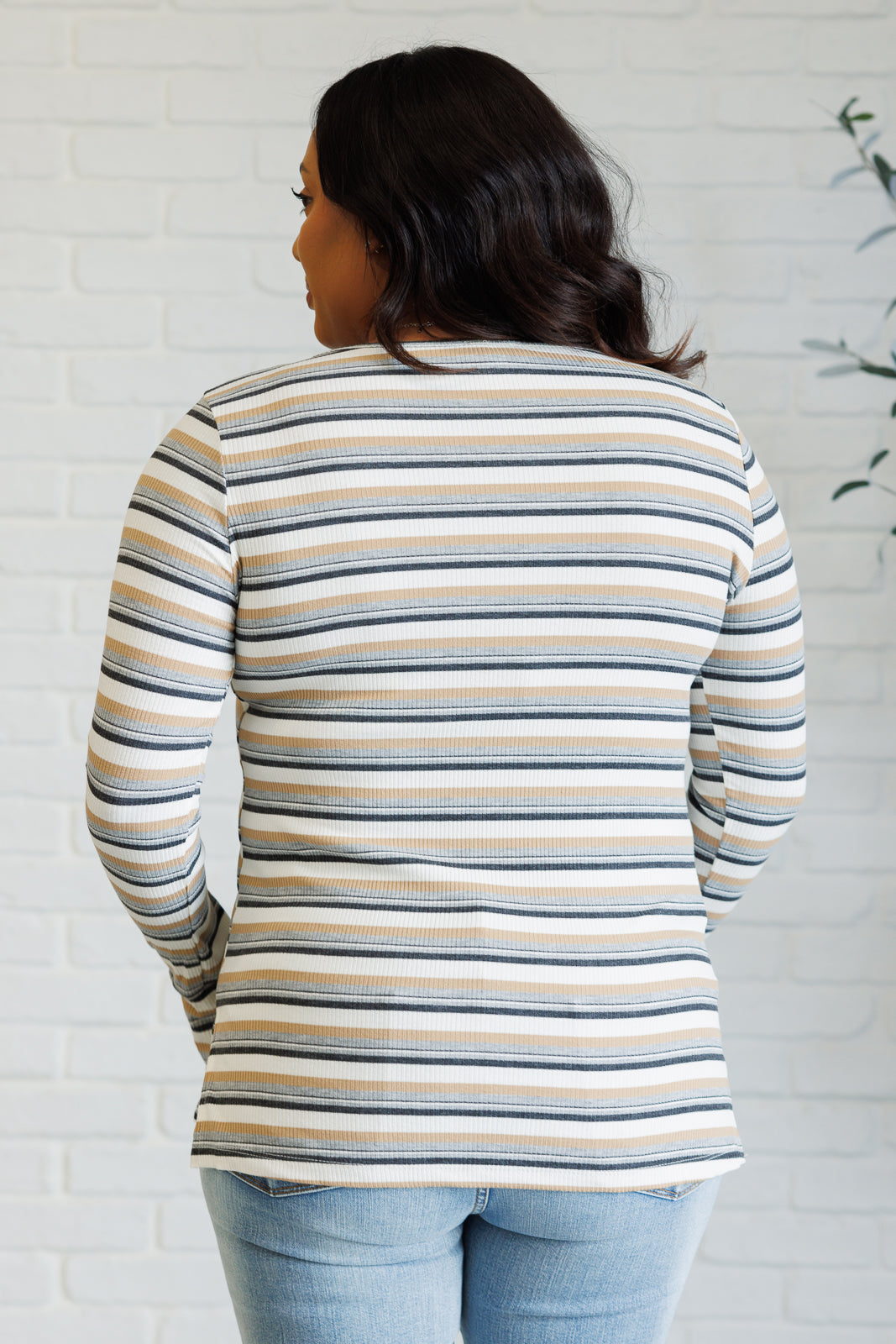 Women's ribbed knit striped top with a round neckline, long sleeves, thumbholes, and side slits.