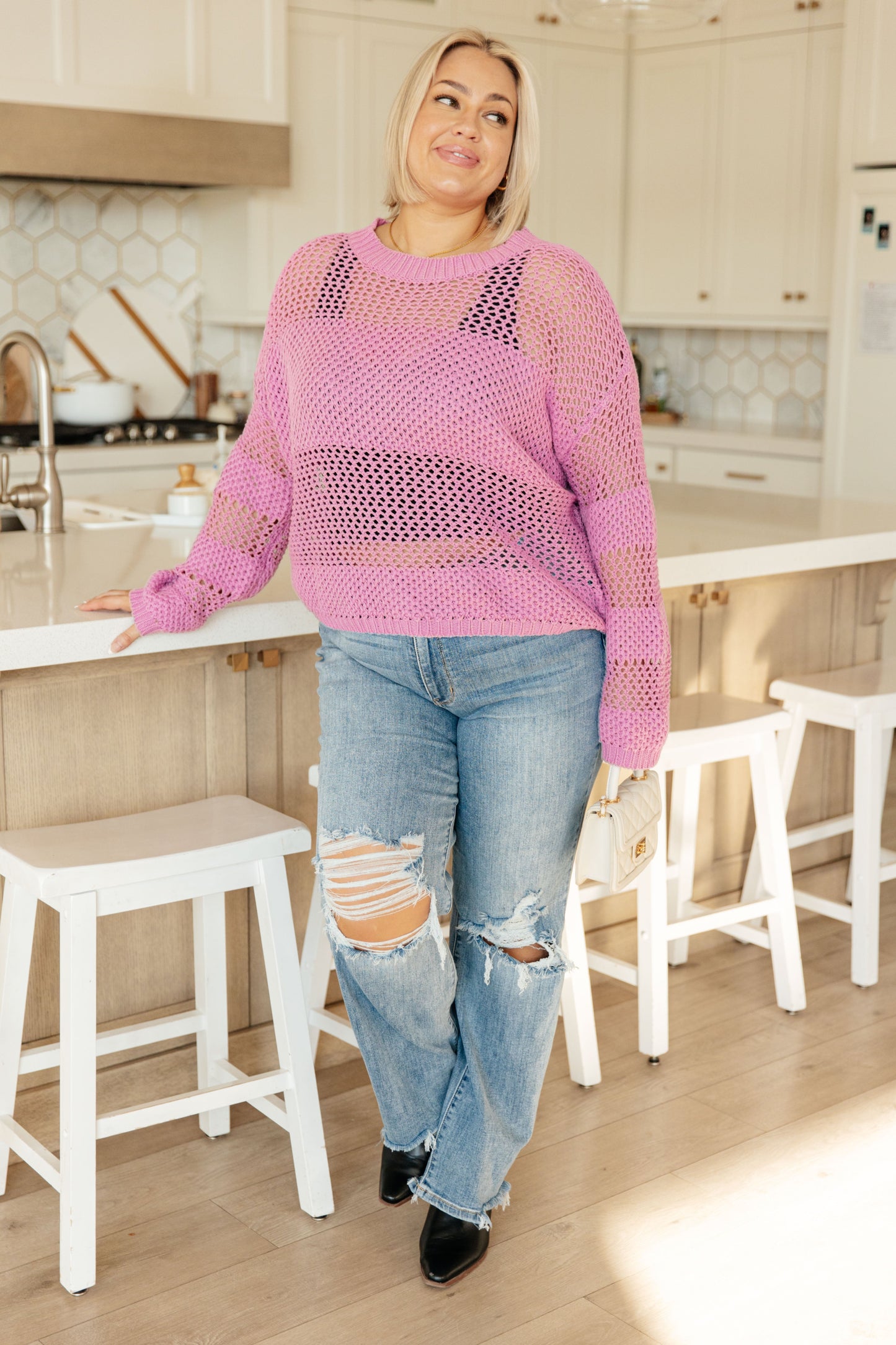Full body view of plus size model wearing the Leia Pink Open Knit Sweater over a black tank, paired with distressed jeans and casual footwear.