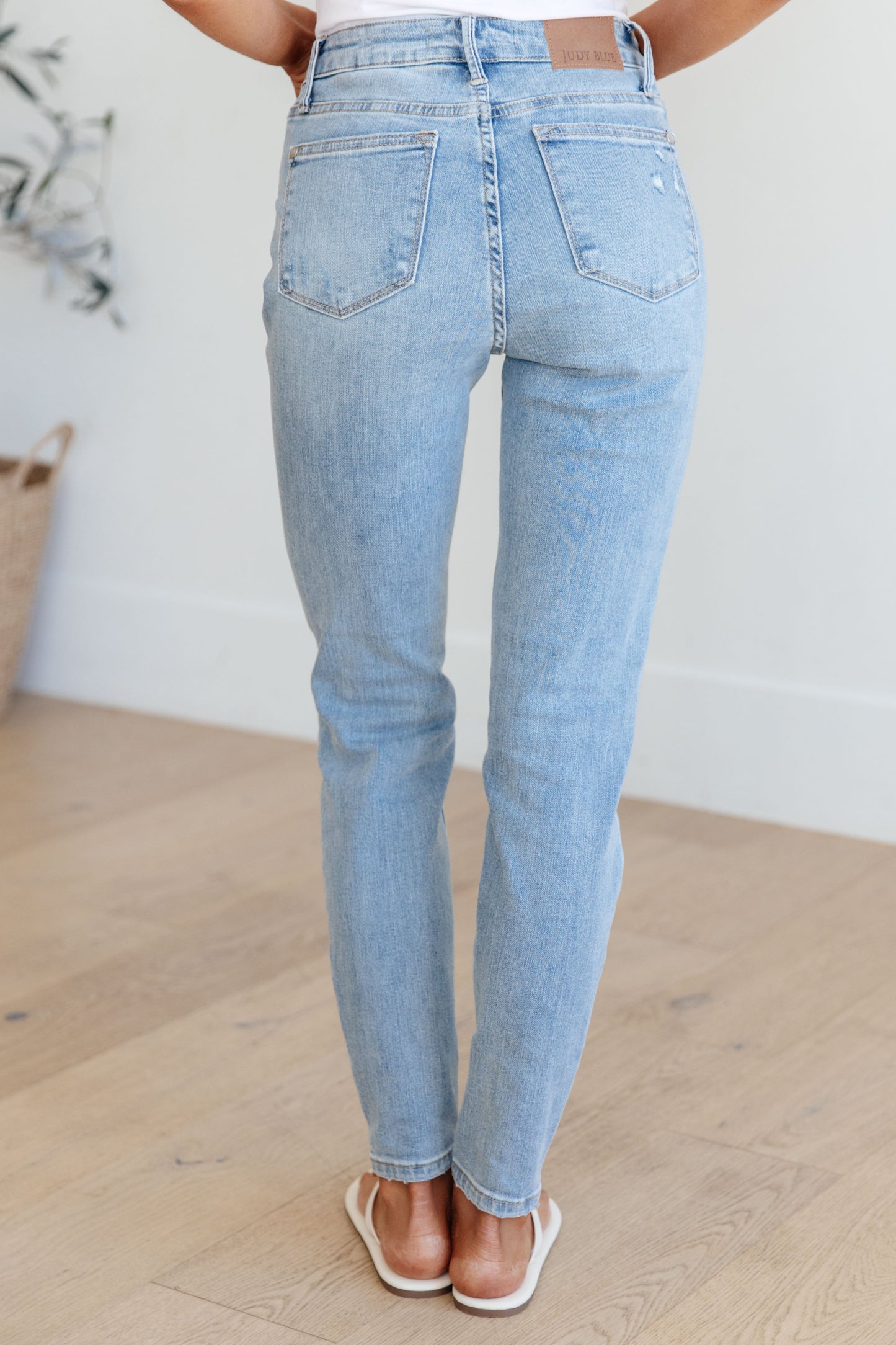 Light wash mid-rise skinny jeans with tummy control and 4-way stretch for comfort. Features distressed details and a zip fly closure.