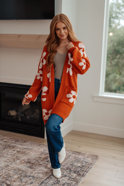 Model wearing Edna Floral Cardigan in burnt orange with oversized fit and open front.