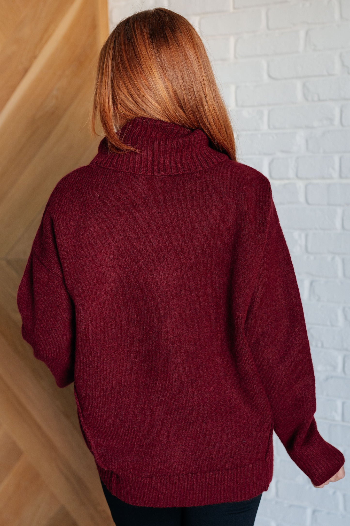 Dark red turtleneck sweater with drop shoulders, ribbed cuffs, and a split, stepped hem.