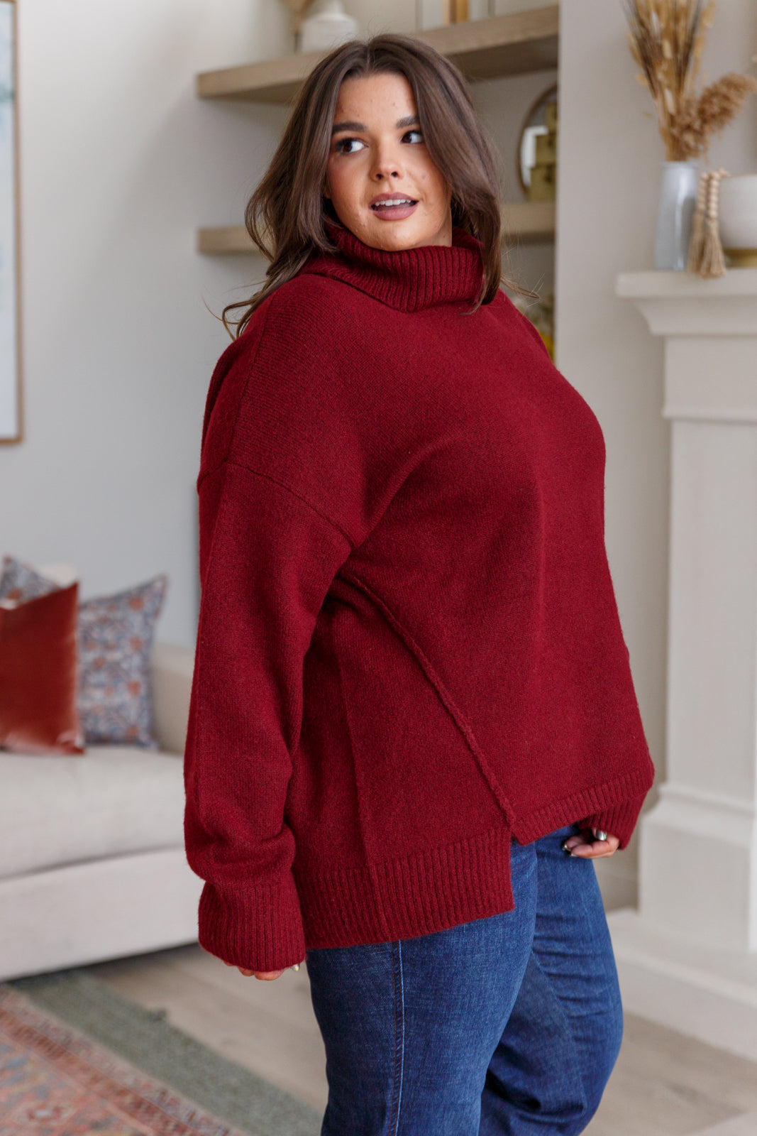 Dark red turtleneck sweater with drop shoulders, ribbed cuffs, and a split, stepped hem.