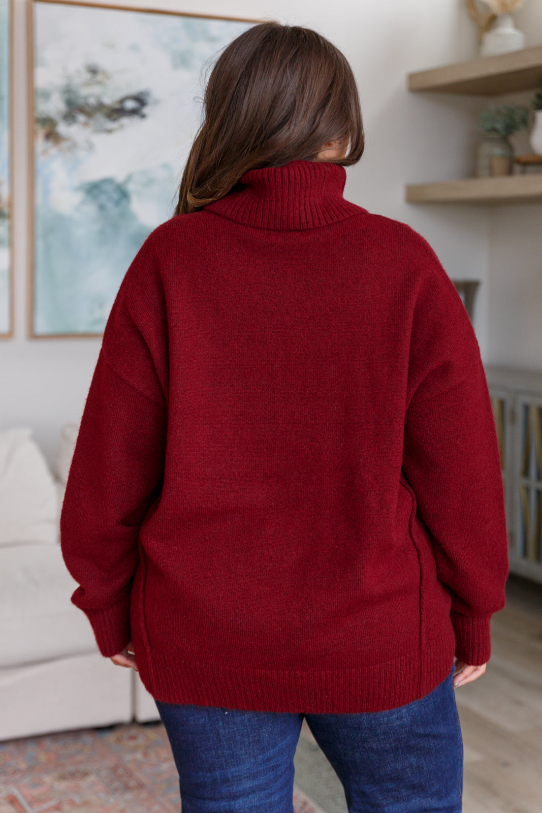 Dark red turtleneck sweater with drop shoulders, ribbed cuffs, and a split, stepped hem.