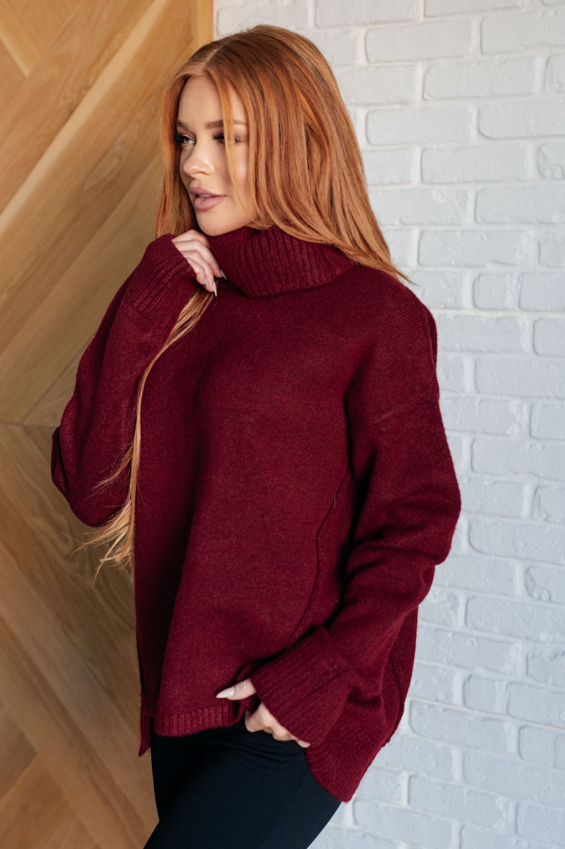 Dark red turtleneck sweater with drop shoulders, ribbed cuffs, and a split, stepped hem.