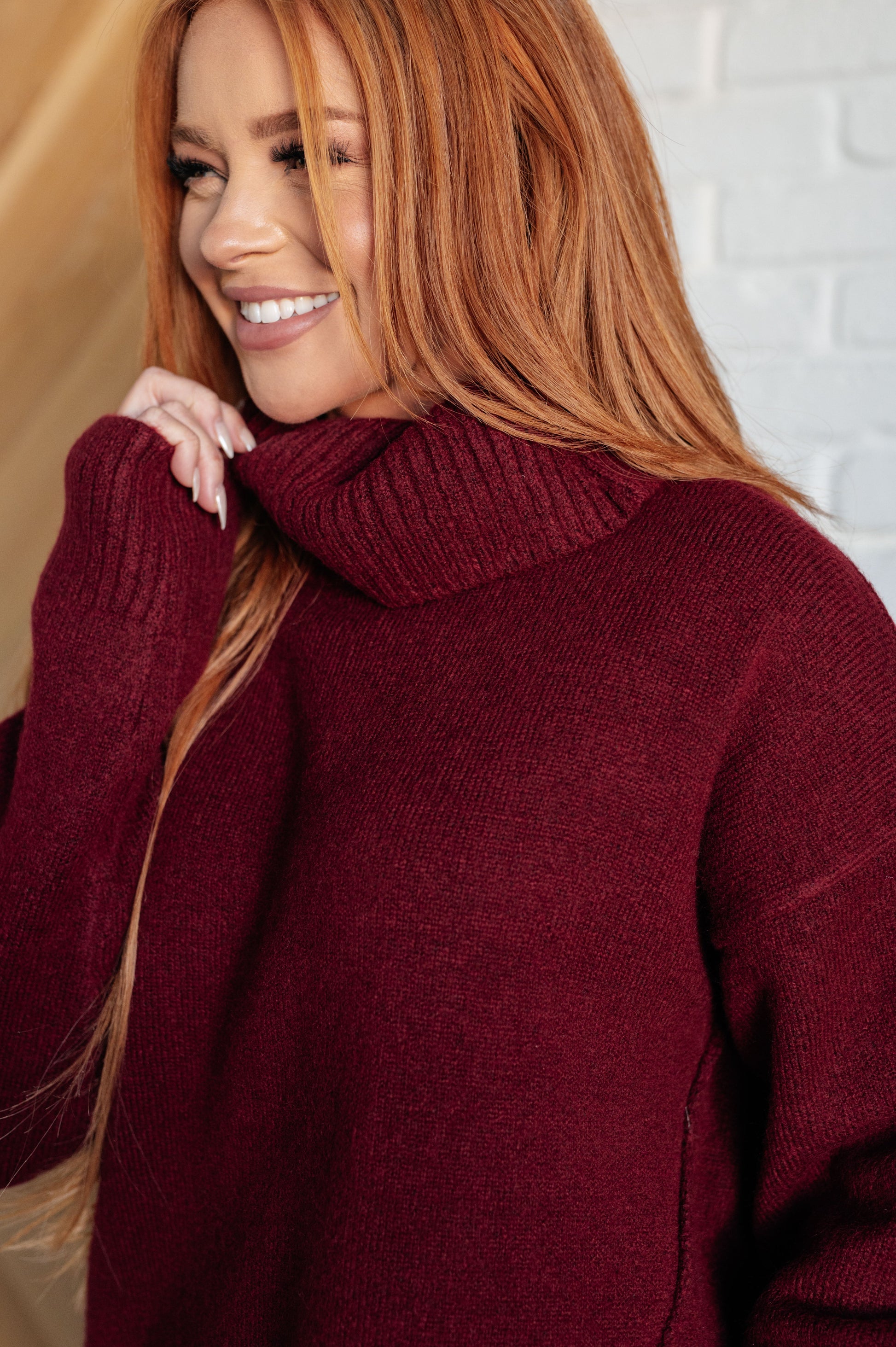 Dark red turtleneck sweater with drop shoulders, ribbed cuffs, and a split, stepped hem.