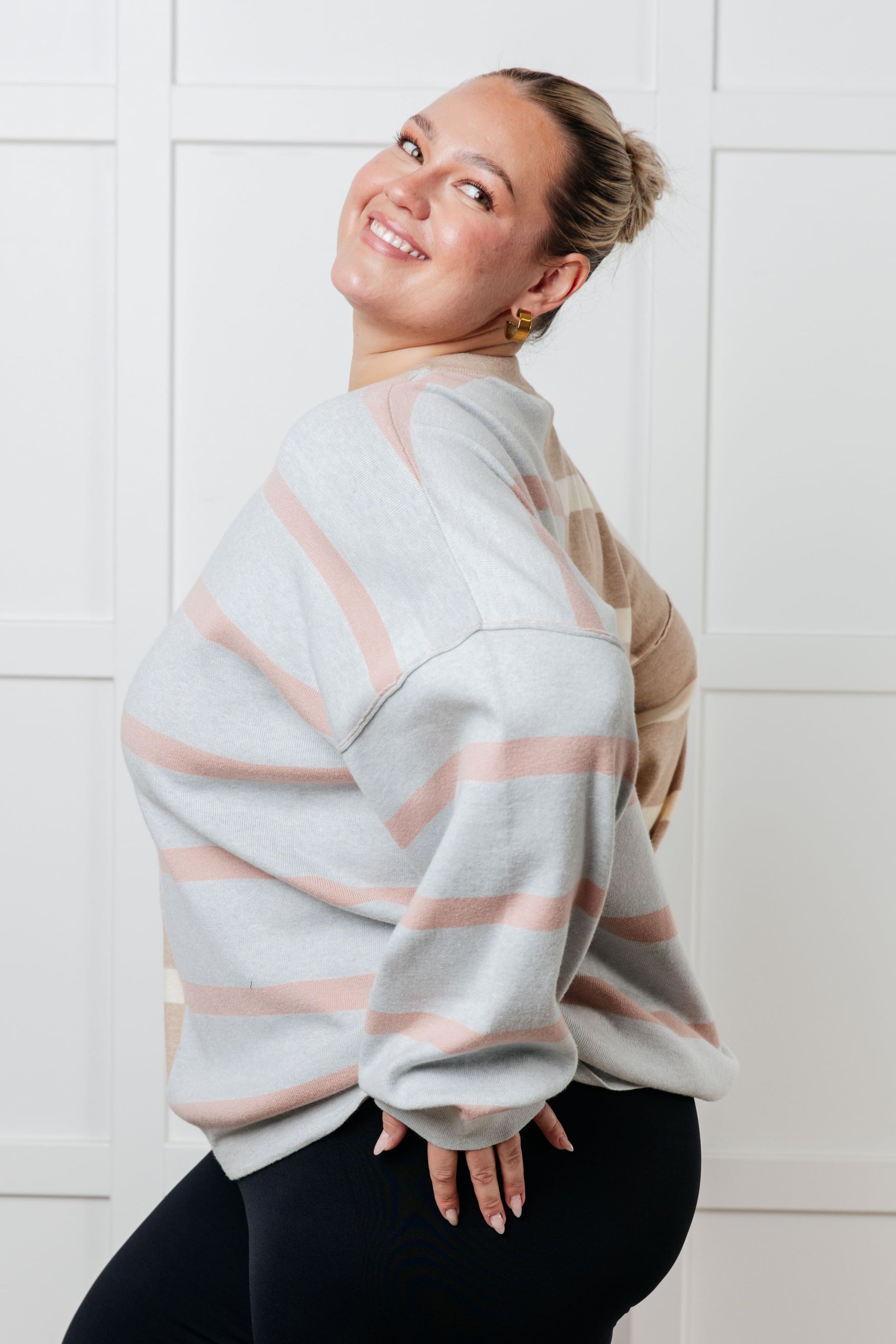 A women's sweater in beige and light gray stripes, made of midweight sweater knit fabric. It features a banded micro-ribbed neckline, long drop-shoulder sleeves with banded micro-ribbed cuffs, exposed seam details, and side slits.