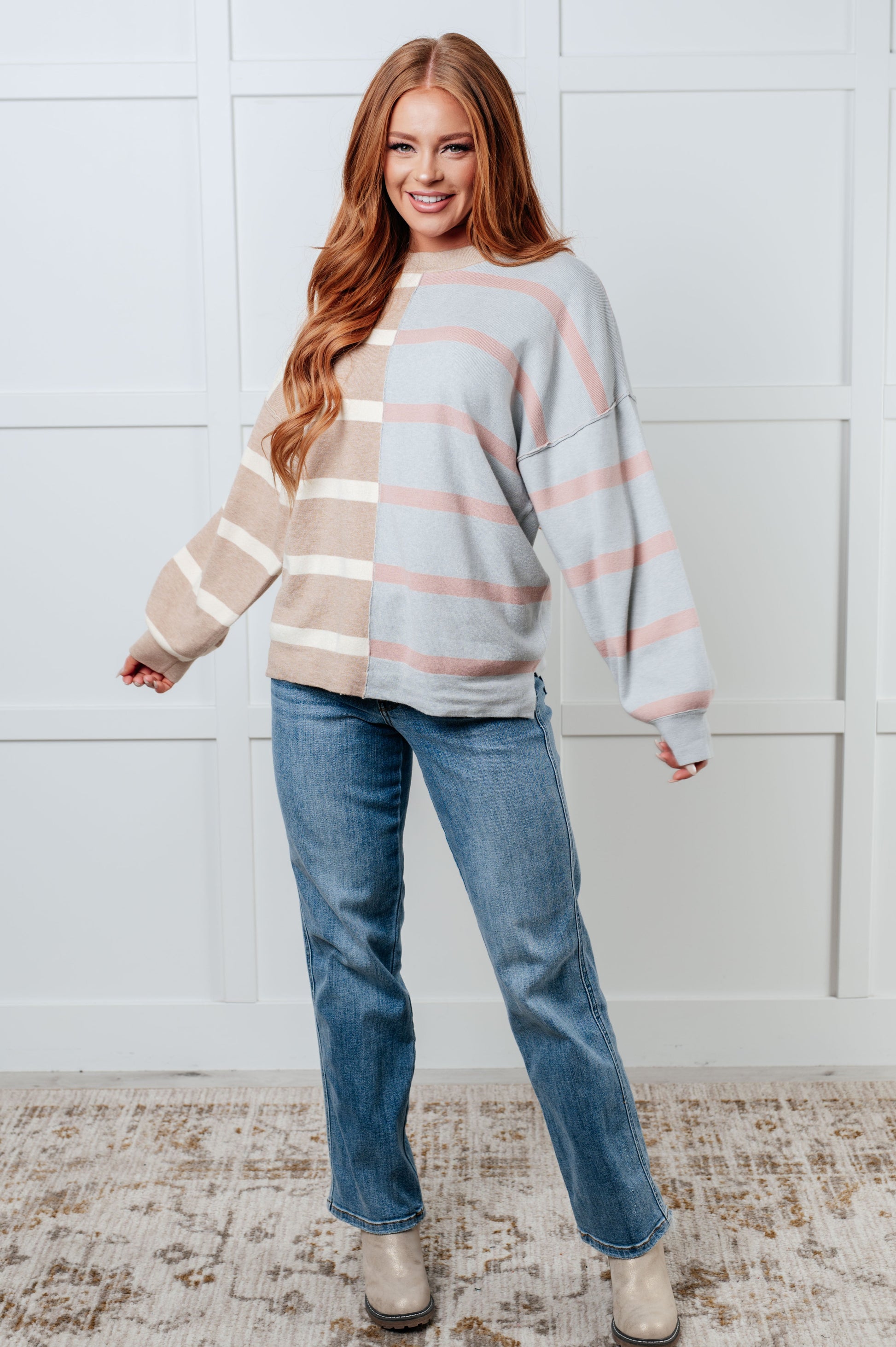 A women's sweater in beige and light gray stripes, made of midweight sweater knit fabric. It features a banded micro-ribbed neckline, long drop-shoulder sleeves with banded micro-ribbed cuffs, exposed seam details, and side slits.