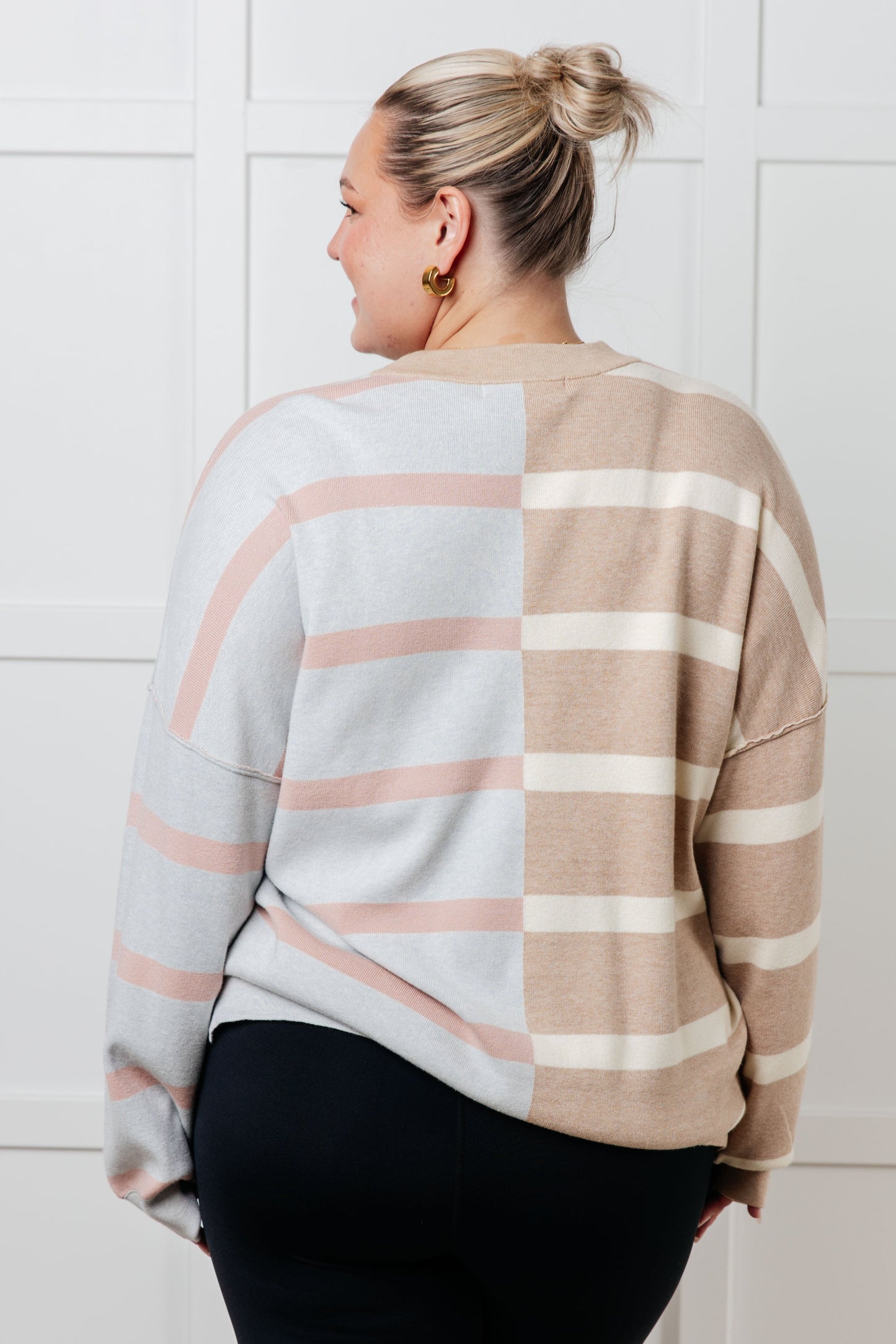 A women's sweater in beige and light gray stripes, made of midweight sweater knit fabric. It features a banded micro-ribbed neckline, long drop-shoulder sleeves with banded micro-ribbed cuffs, exposed seam details, and side slits.