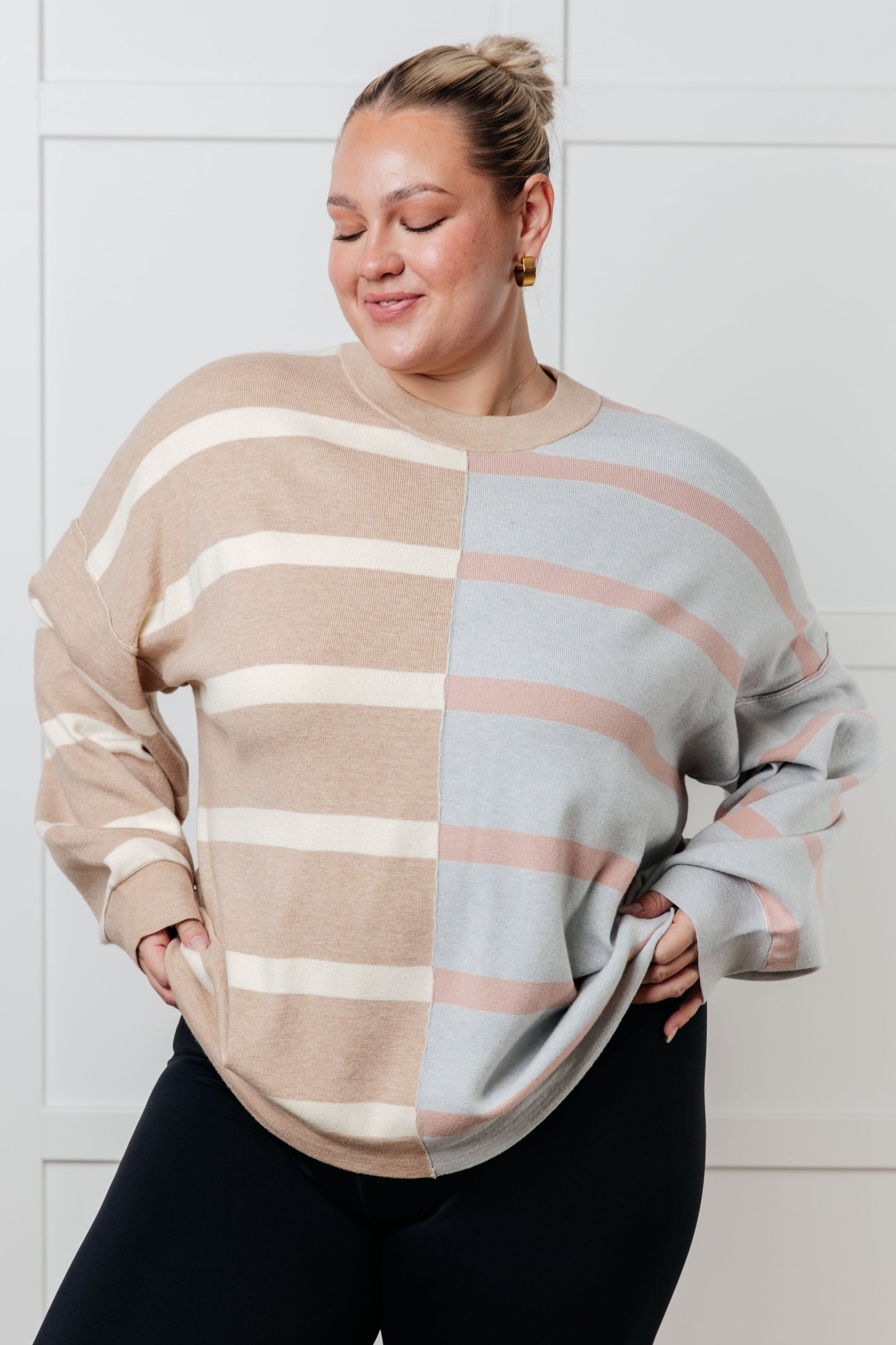 A women's sweater in beige and light gray stripes, made of midweight sweater knit fabric. It features a banded micro-ribbed neckline, long drop-shoulder sleeves with banded micro-ribbed cuffs, exposed seam details, and side slits.