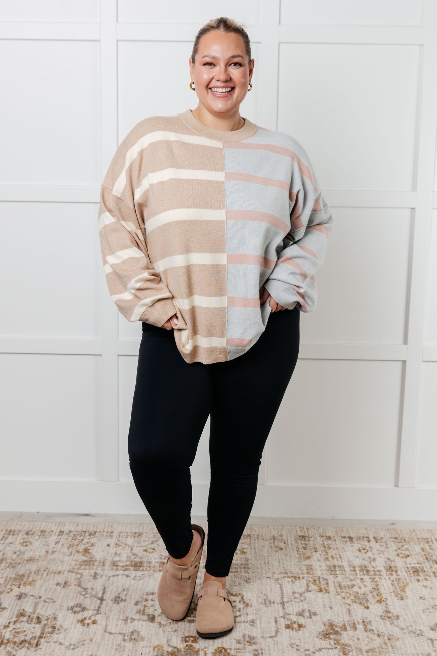 A women's sweater in beige and light gray stripes, made of midweight sweater knit fabric. It features a banded micro-ribbed neckline, long drop-shoulder sleeves with banded micro-ribbed cuffs, exposed seam details, and side slits.