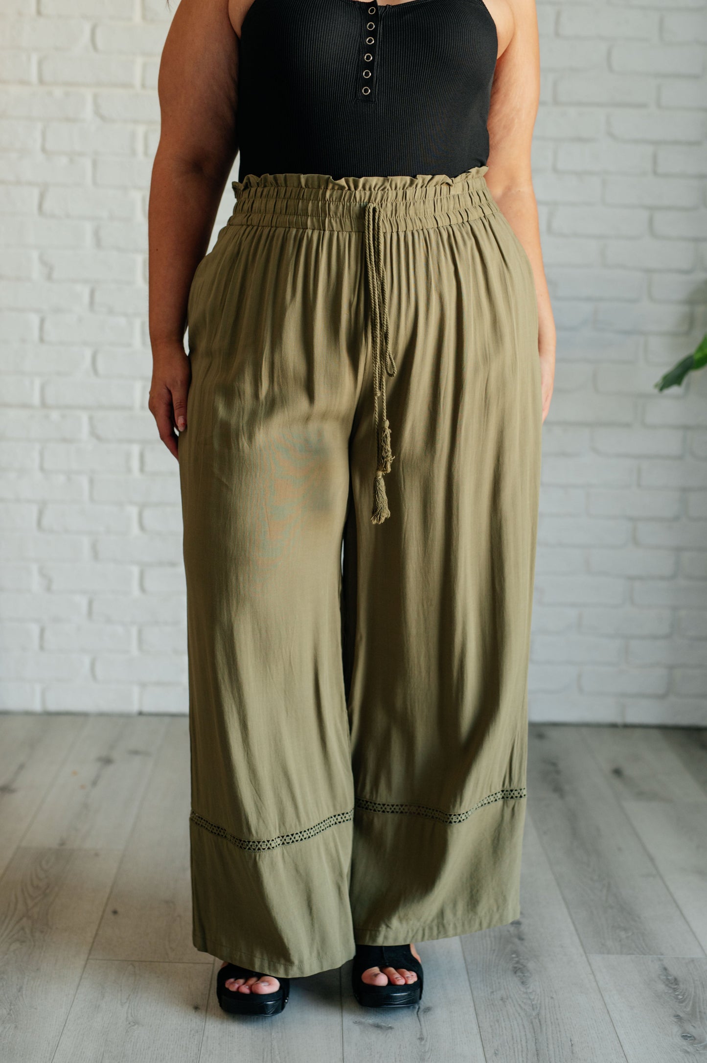 Olive wide-leg pants with a ruffled elastic waistband, geometric embroidery, and tasseled drawstring