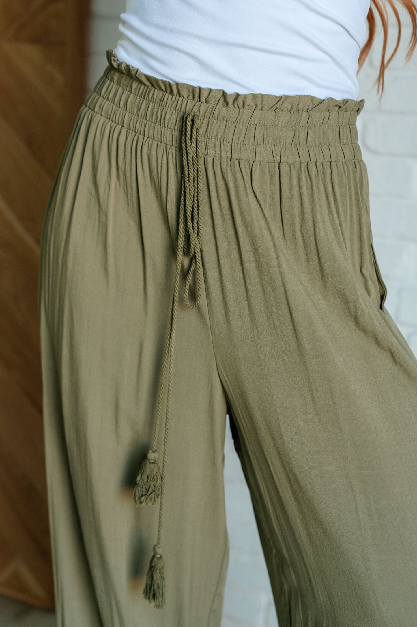 Olive wide-leg pants with a ruffled elastic waistband, geometric embroidery, and tasseled drawstring