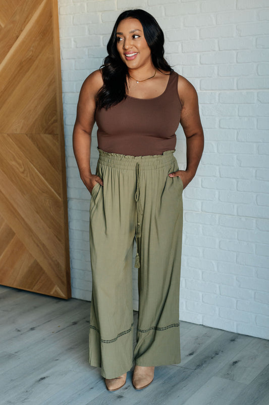 Plus size model wearing Kendall Wide Leg Pants in olive with ruffled waist, tassel drawstring, and wide leg silhouette.